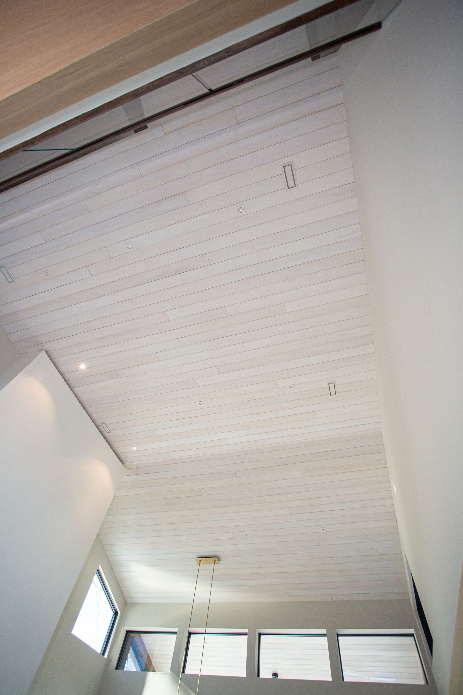 White wooden ceiling with recessed lighting and a hanging light fixture.