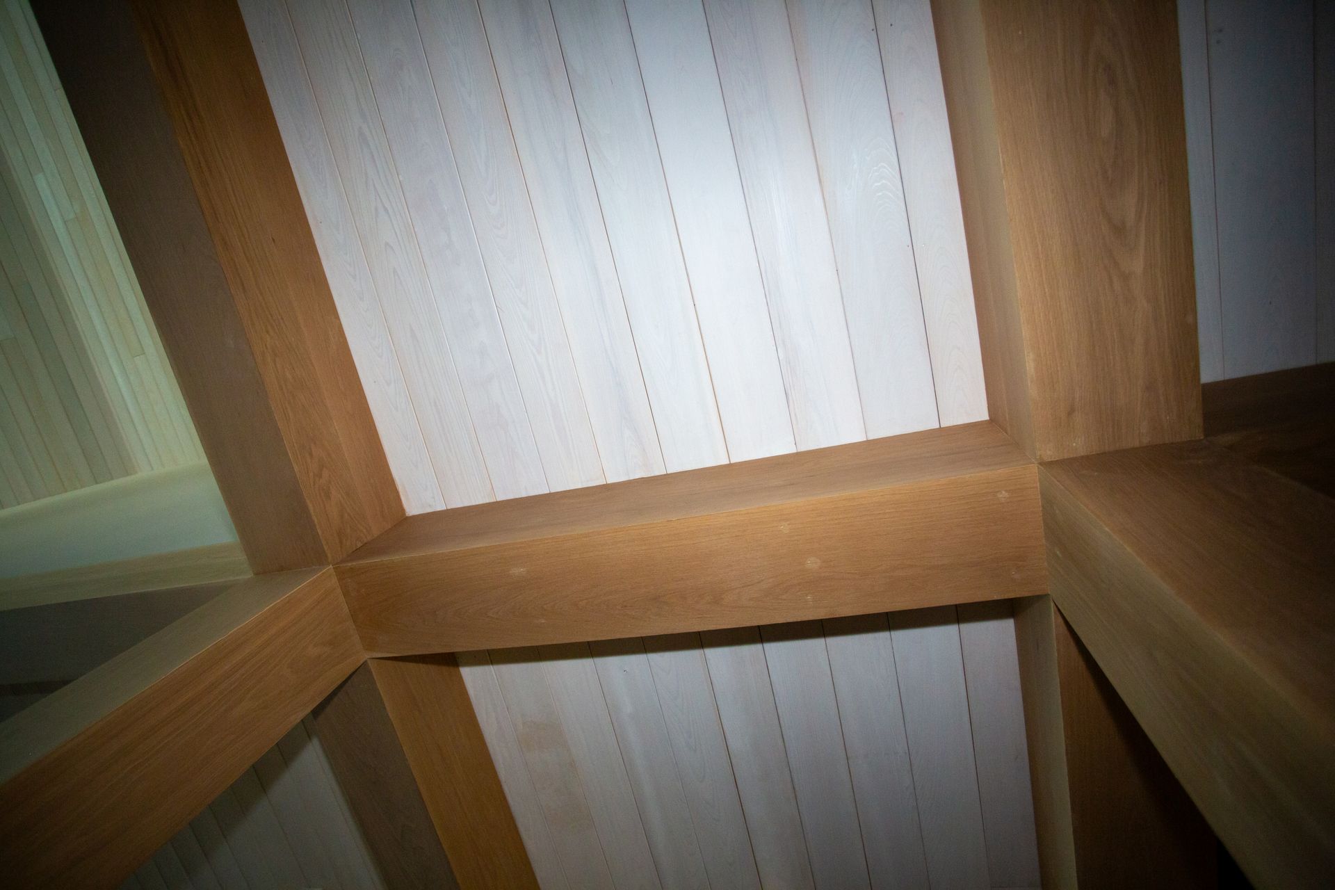 Wooden ceiling with light-colored panels and dark wooden beams forming a grid pattern.