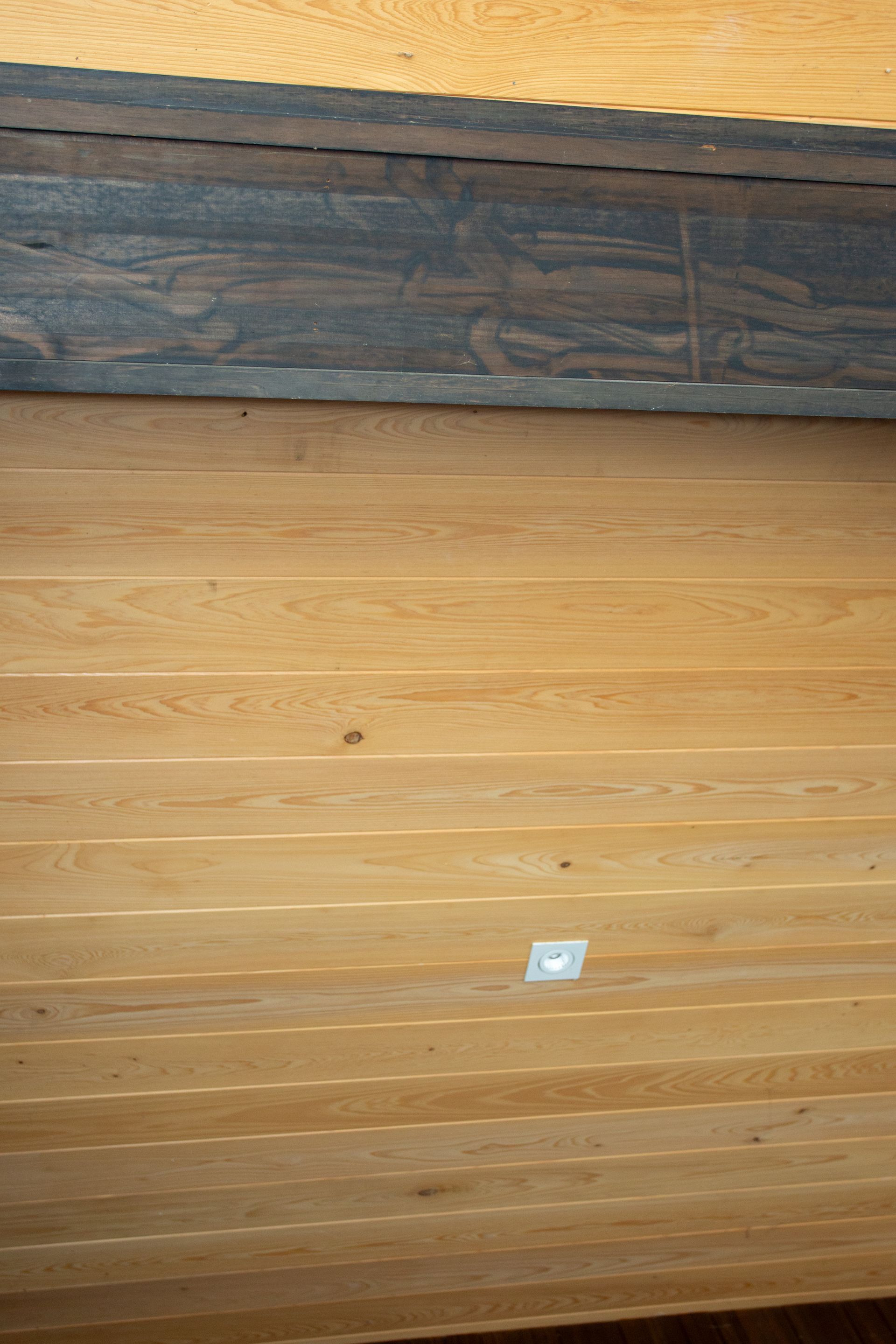 Wooden ceiling with a dark stained beam, and small square light.