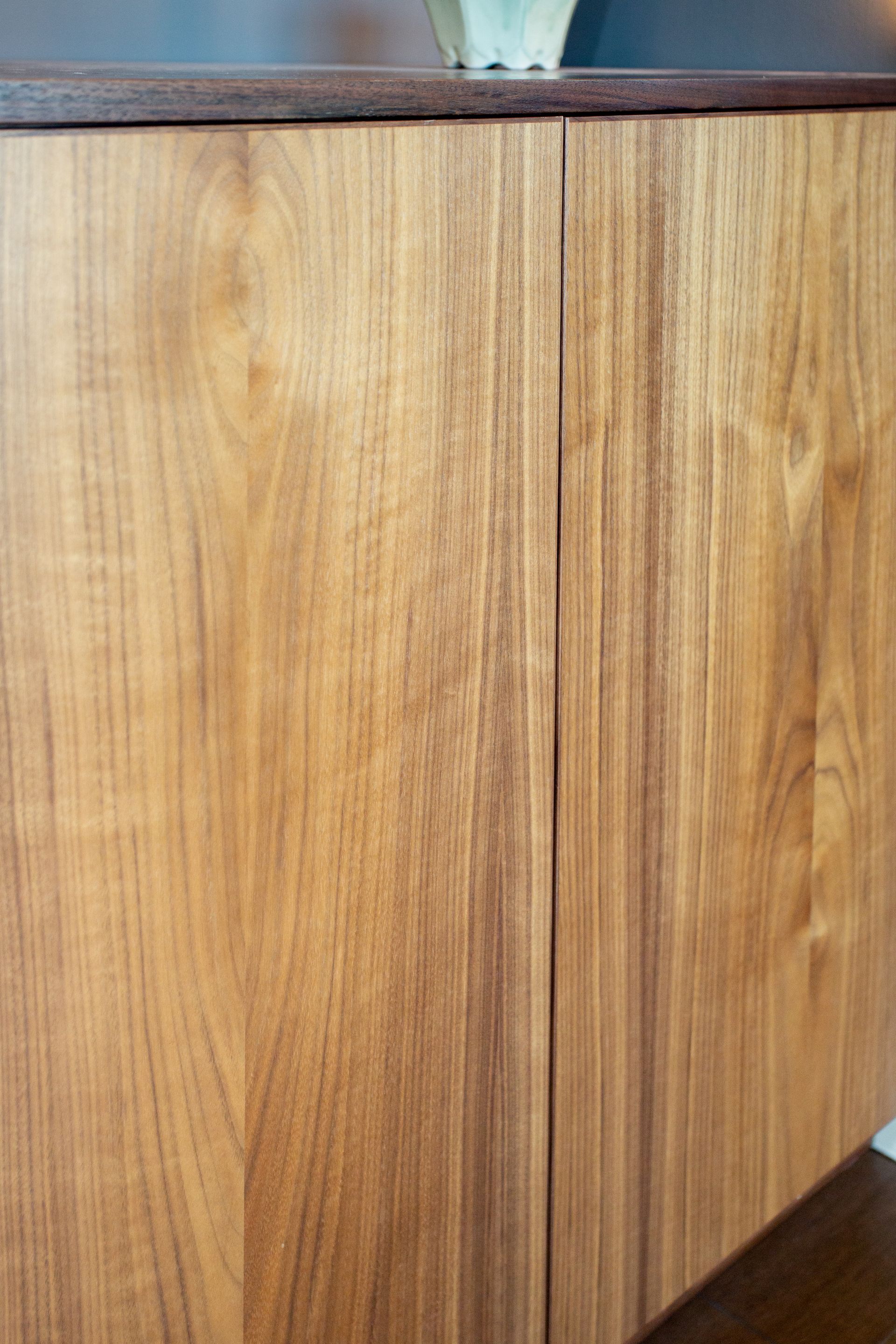 Wooden cabinet doors with vertical grain, dark trim, and a small gap between them.