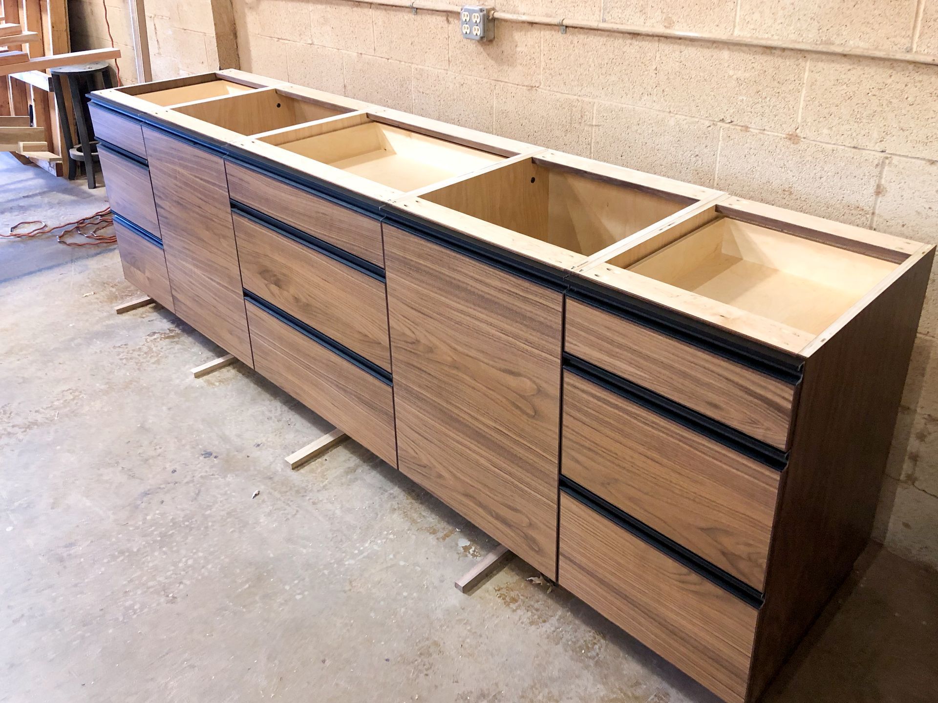 Wooden bathroom vanity cabinet with drawers and open sink compartments.