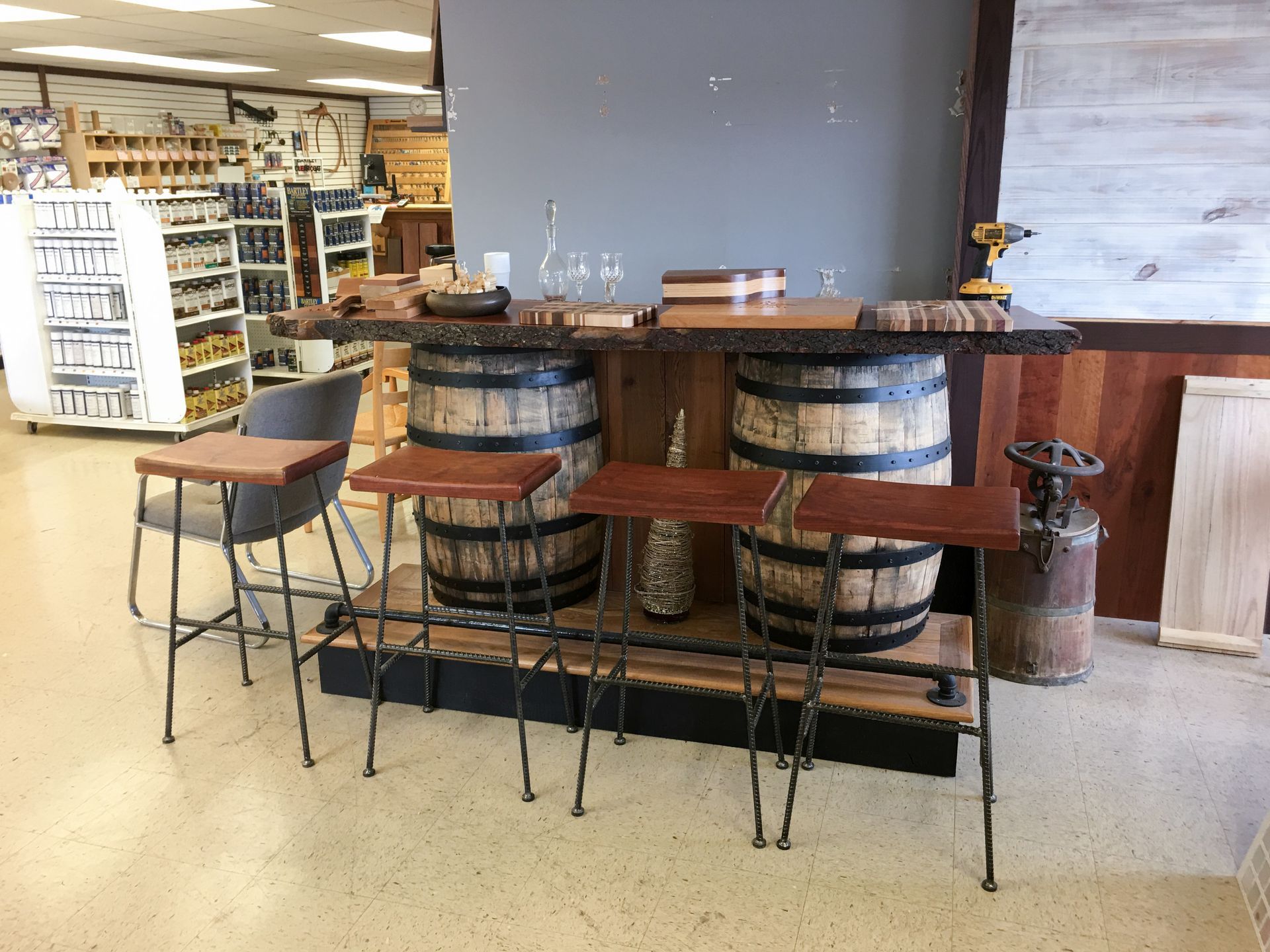 Bar with two barrels, wooden top, stools, and shop interior.