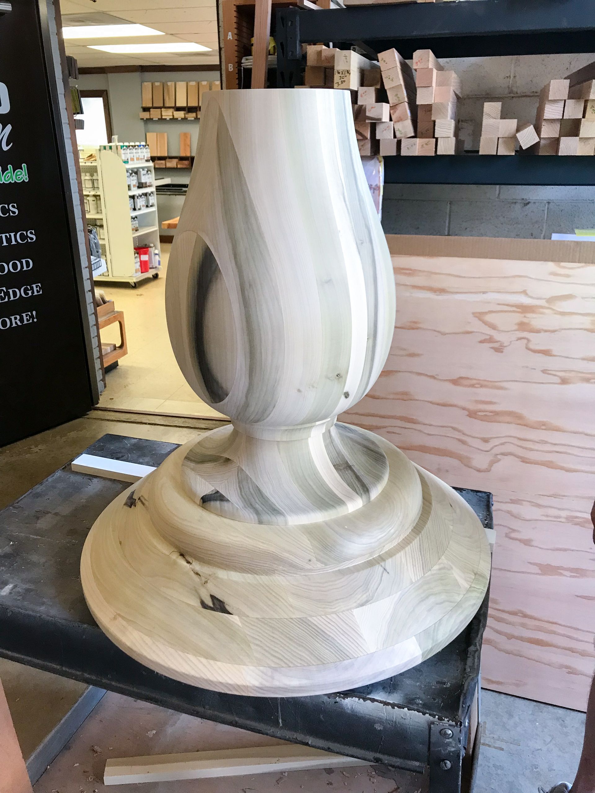 Wooden table base in a workshop, light-colored wood, carved design.