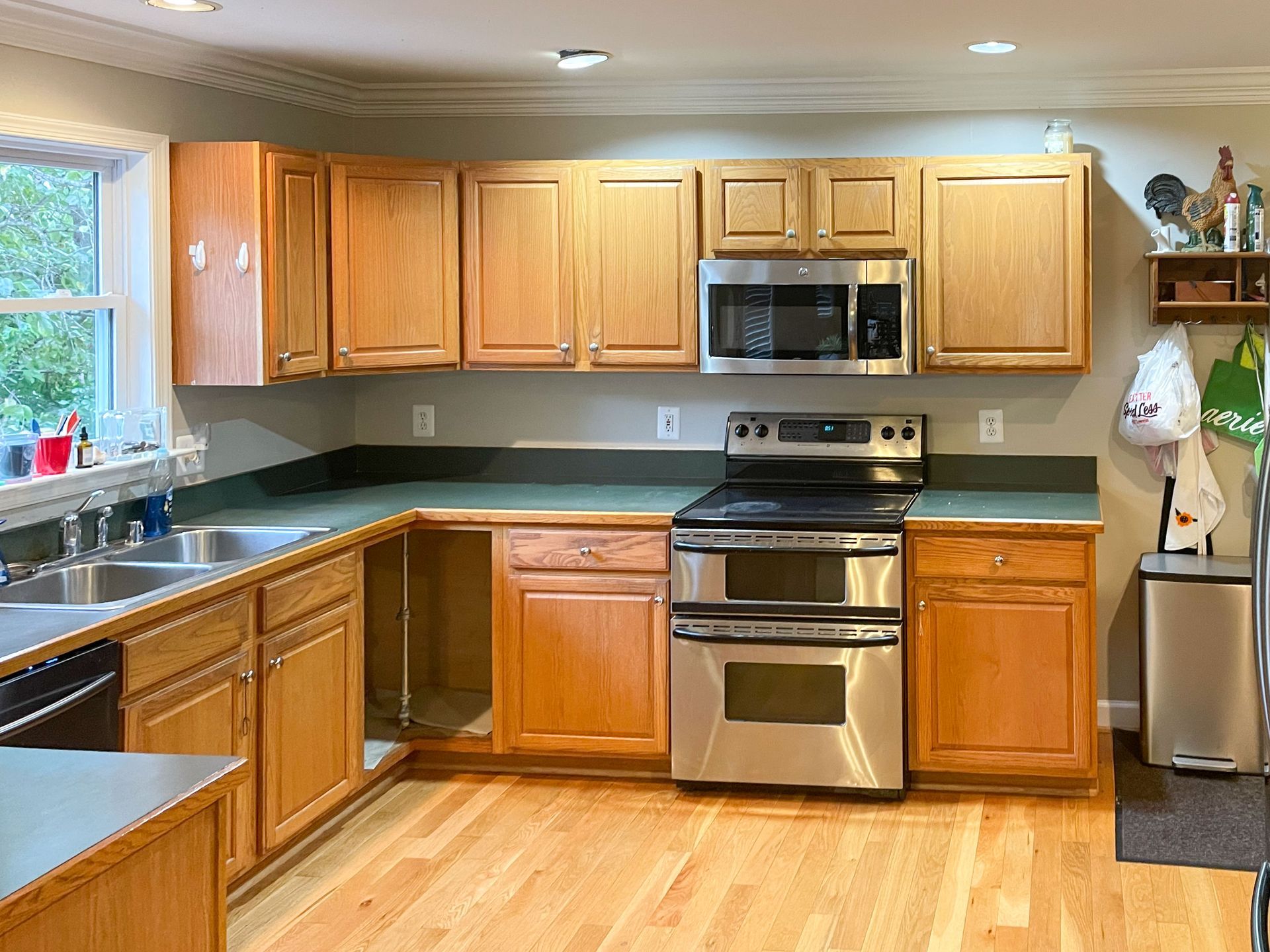 Kitchen with light wood cabinets, stainless steel appliances, and green countertops.