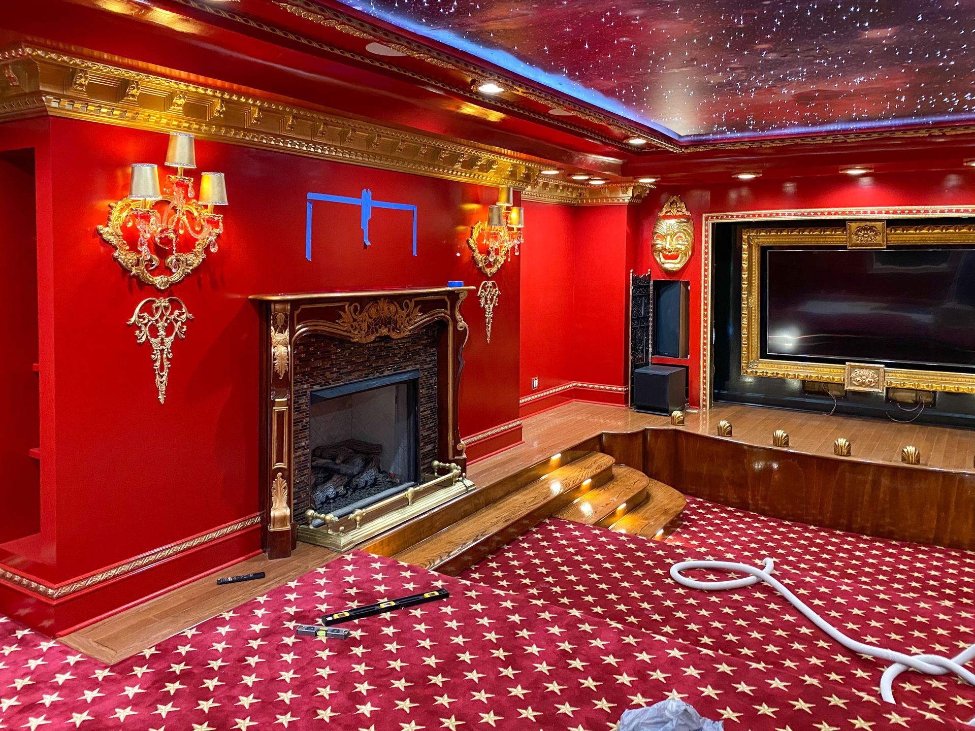 Luxurious red room with gold trim, fireplace, and starry ceiling, with a sunken bed area.