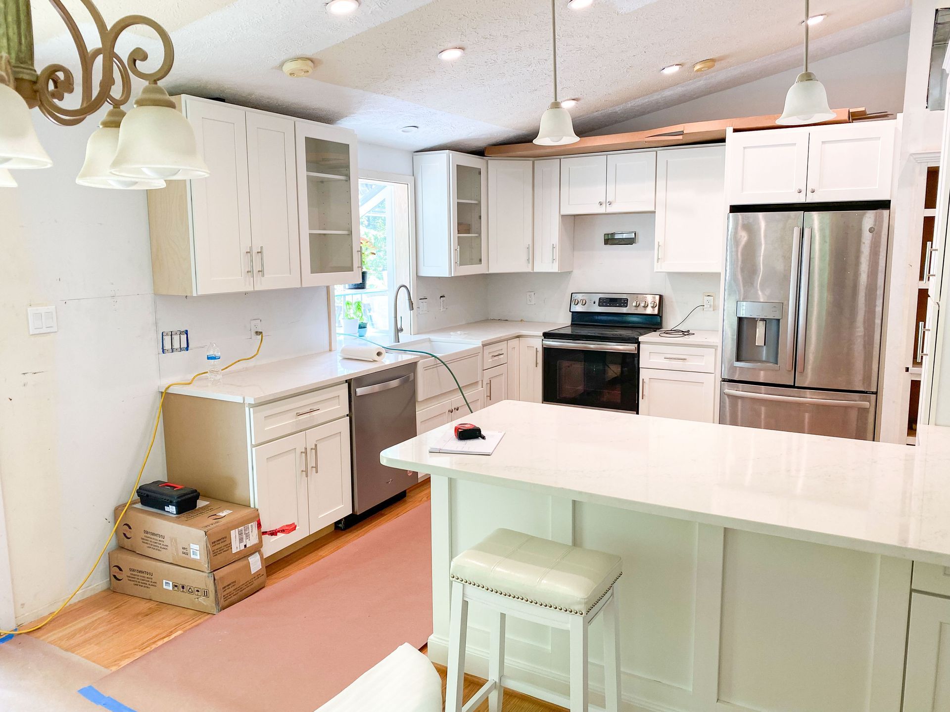 White kitchen with new cabinets, countertops, and appliances during renovation.