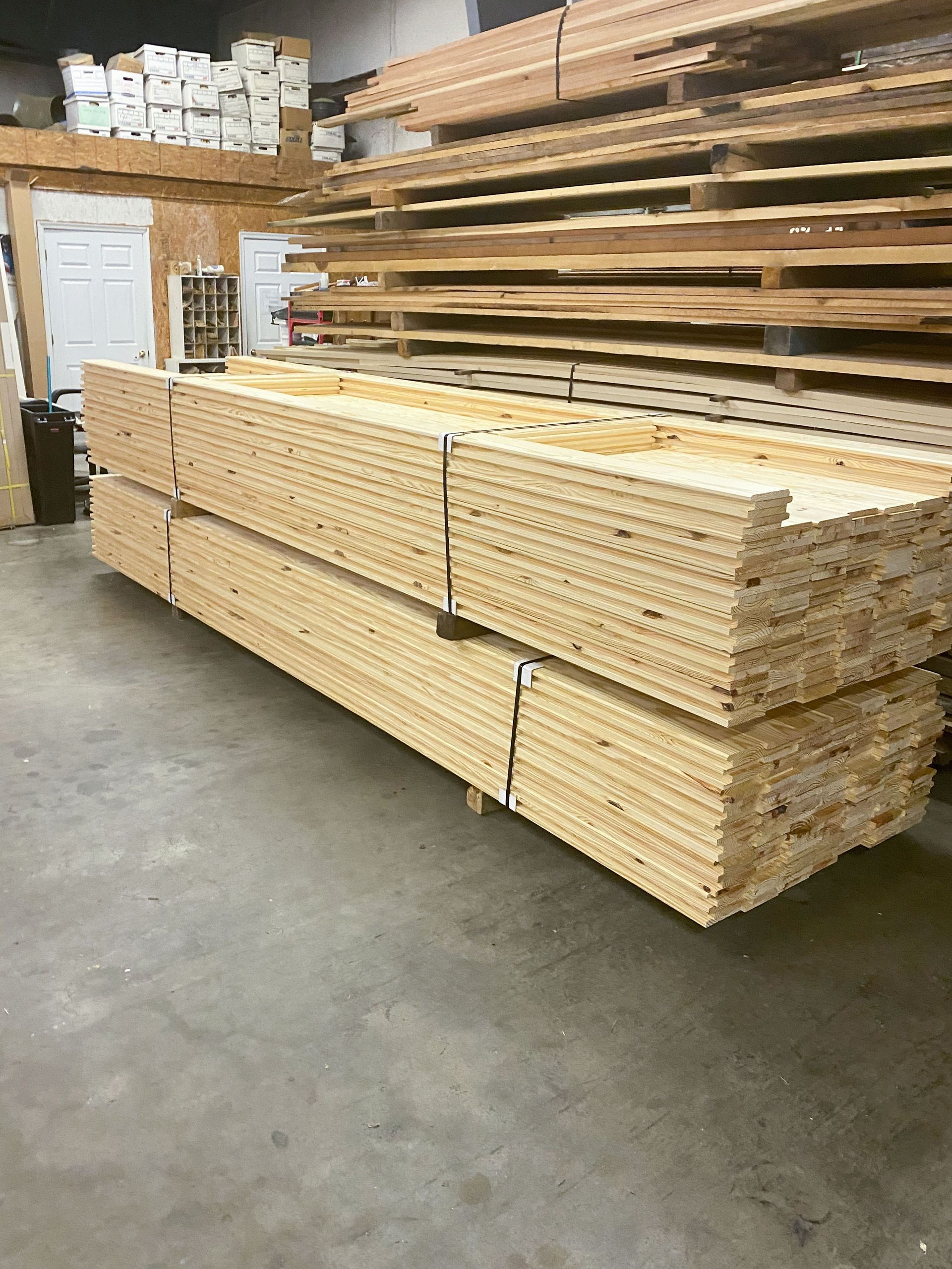 Stacks of wooden boards in a lumberyard, bundled and ready for purchase.