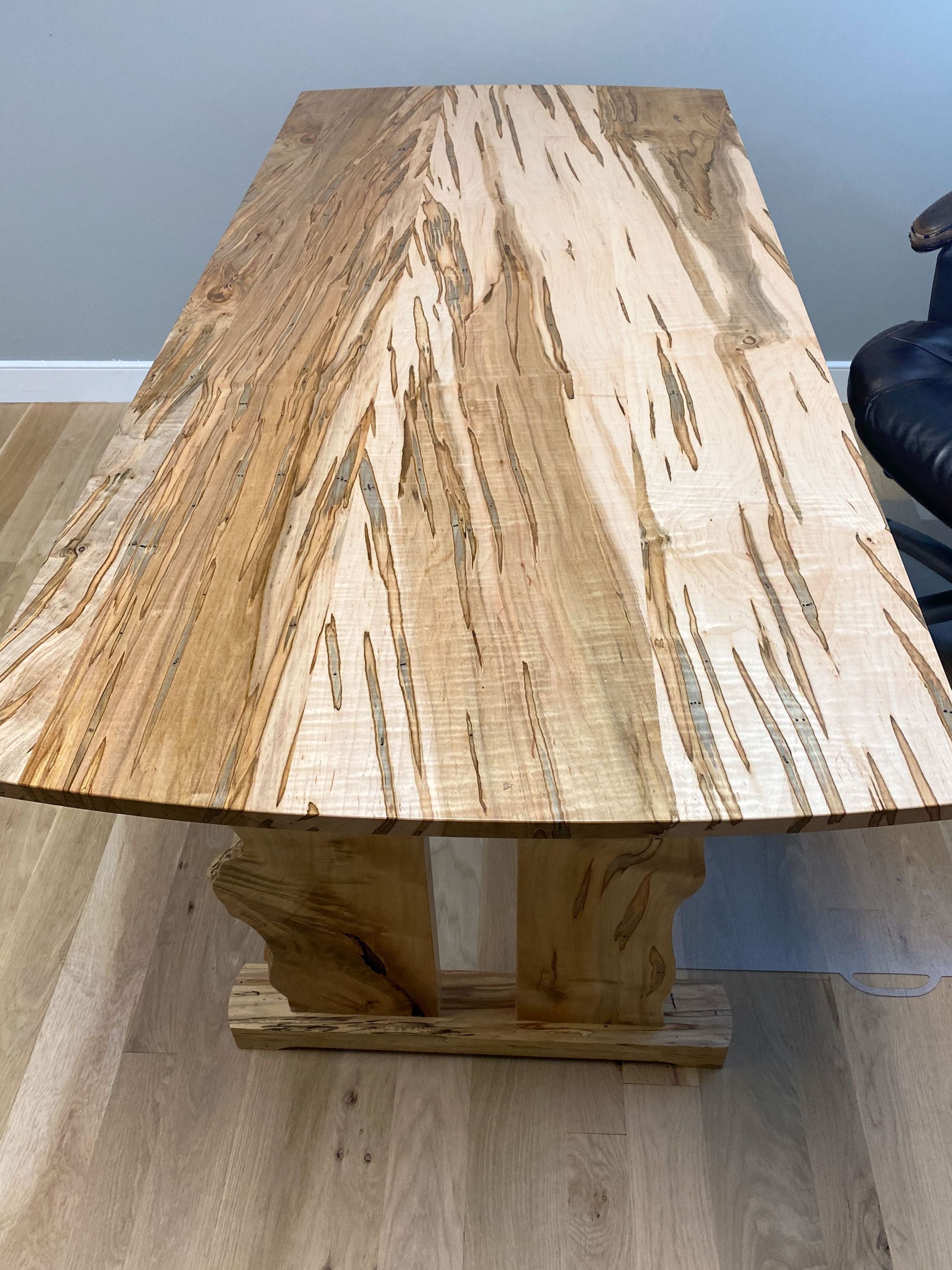 Wooden table with unique grain pattern, supported by two wooden tree trunk-like legs.