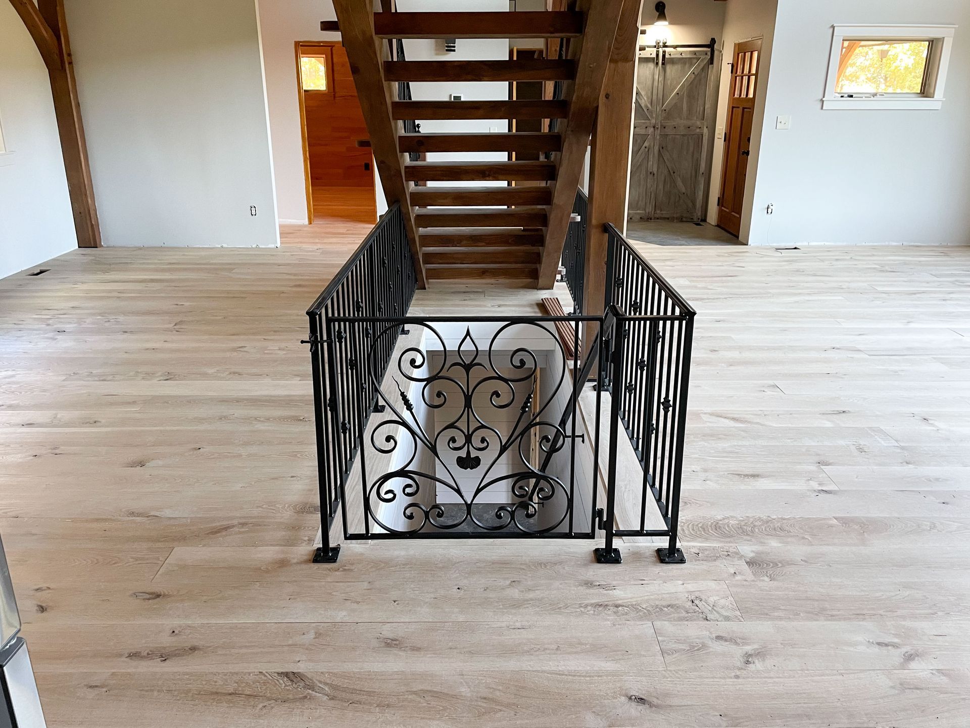 Interior with light wood floors, a wrought iron stairwell gate, and wooden stairs leading upward.