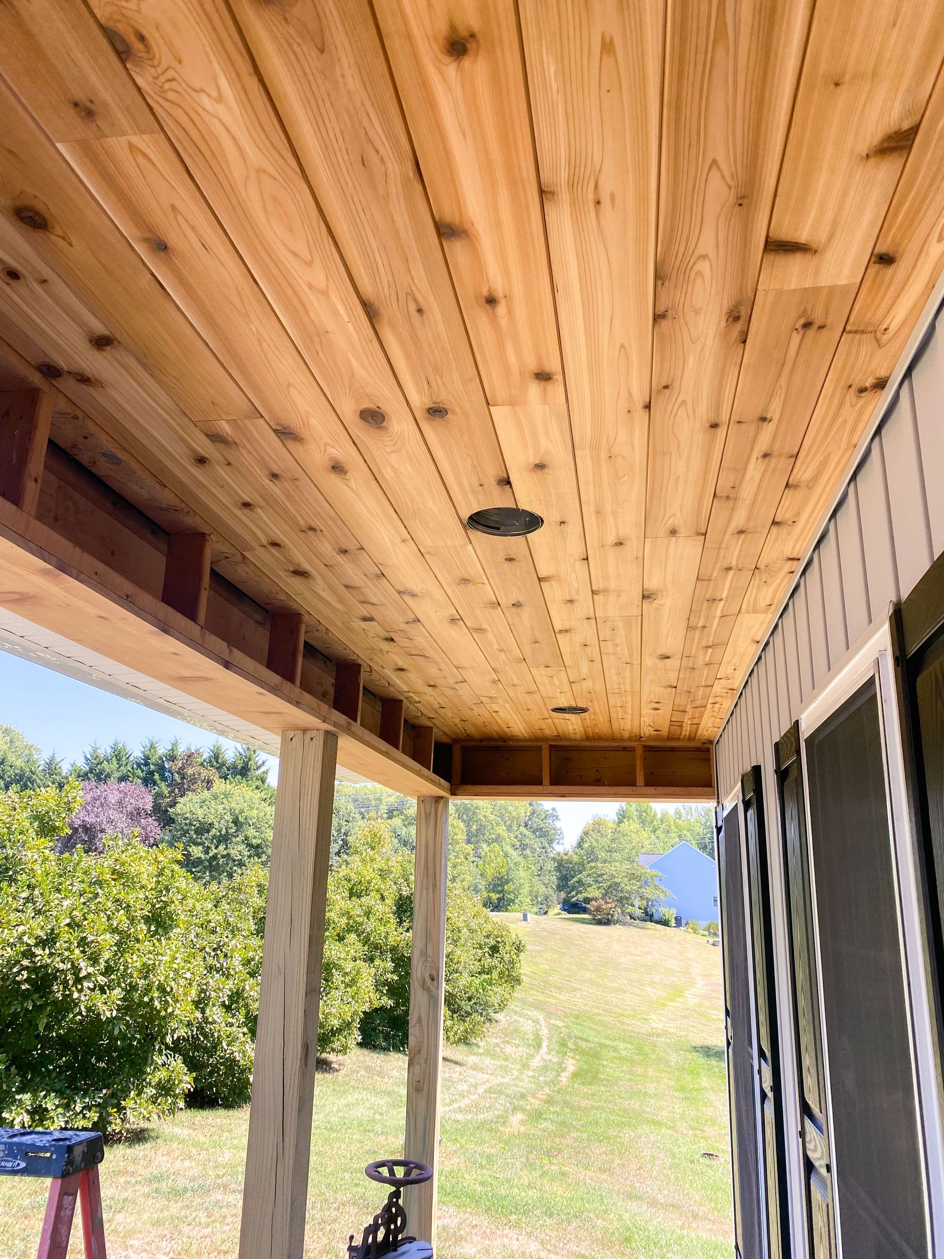 Cedar plank ceiling with recessed lighting installed on a porch.