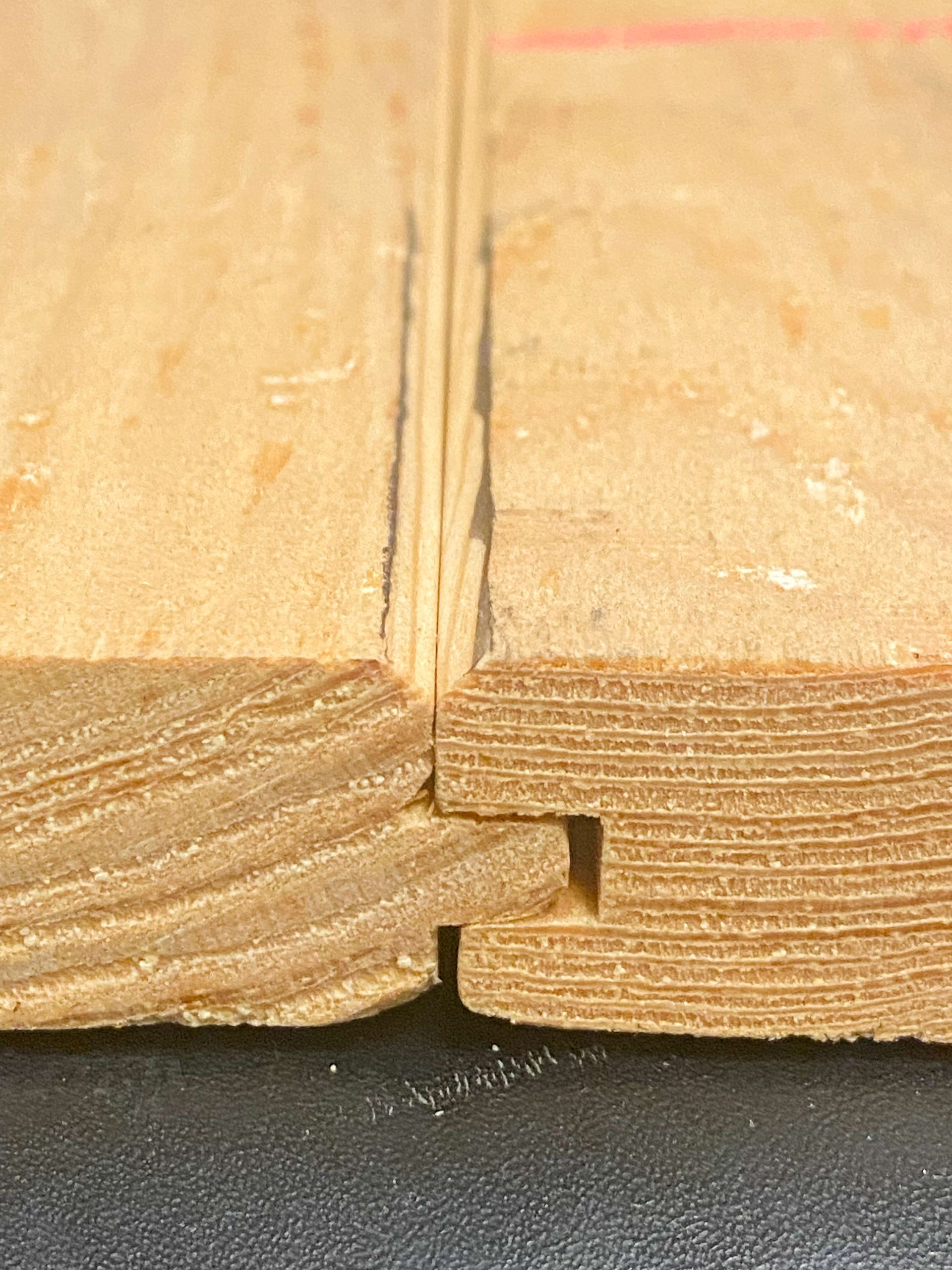 Close-up of two wooden planks joined together with a tongue-and-groove joint, showing the edge grain and connection.