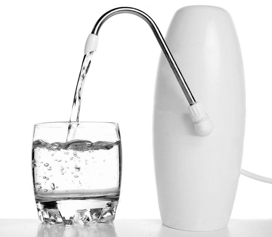 A white countertop water purifier dispensing water into a clear glass.