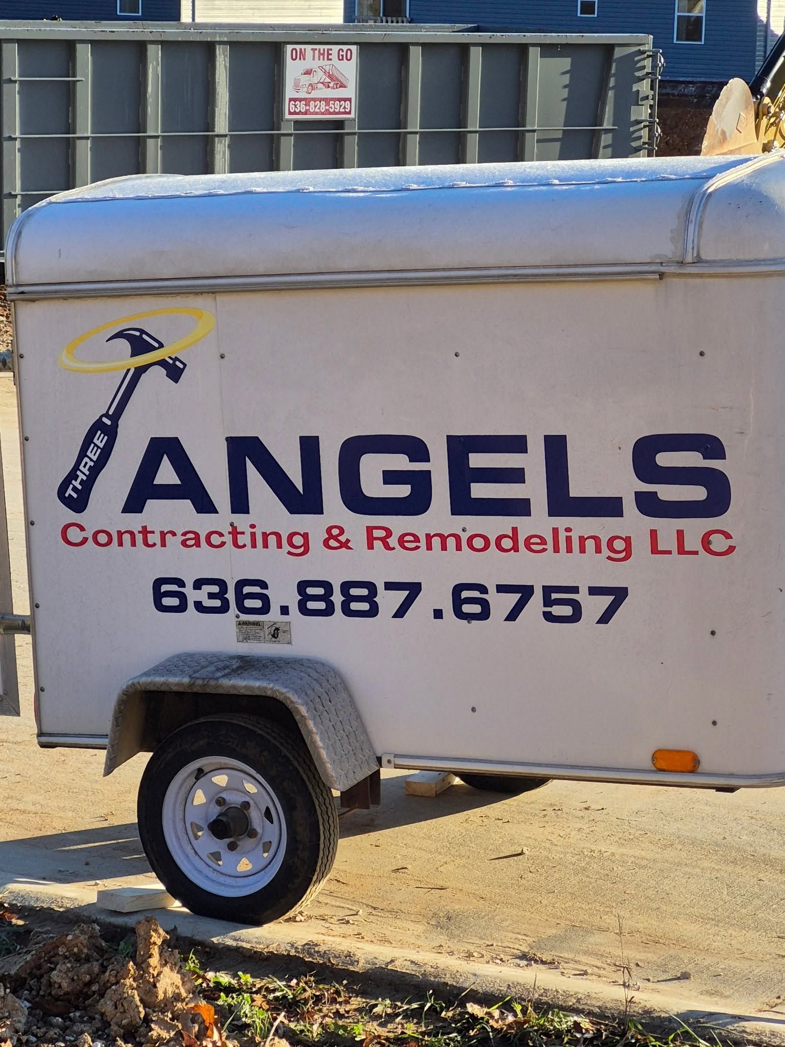 White utility trailer with ANGELS Contracting & Remodeling LLC logo and phone number outdoors