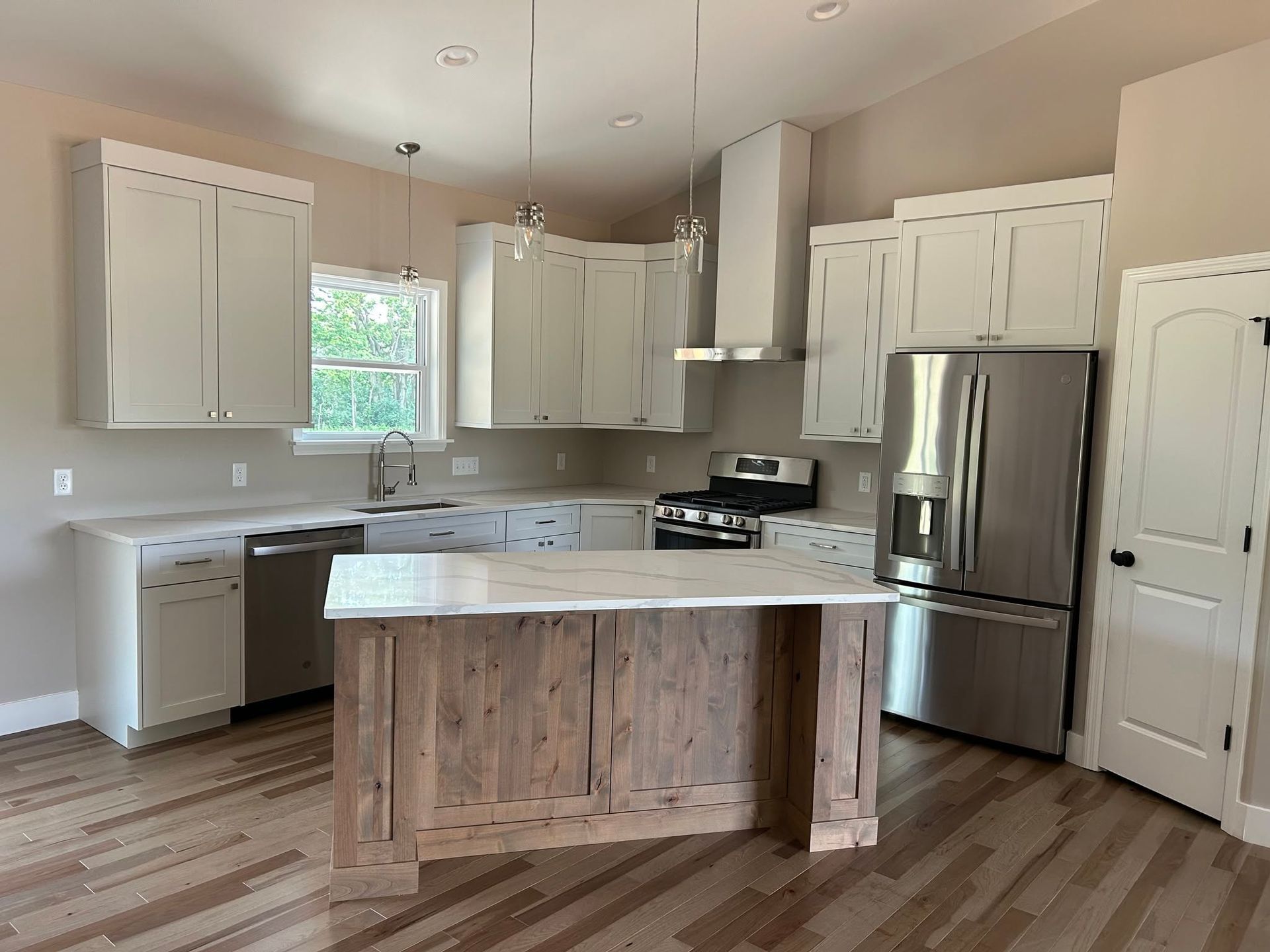 Bright kitchen with white cabinets, stainless steel appliances, and a wood island on light hardwood floors