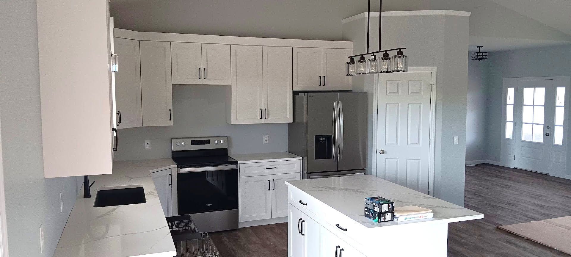 Bright white kitchen with island, black stove, stainless fridge, and light gray flooring