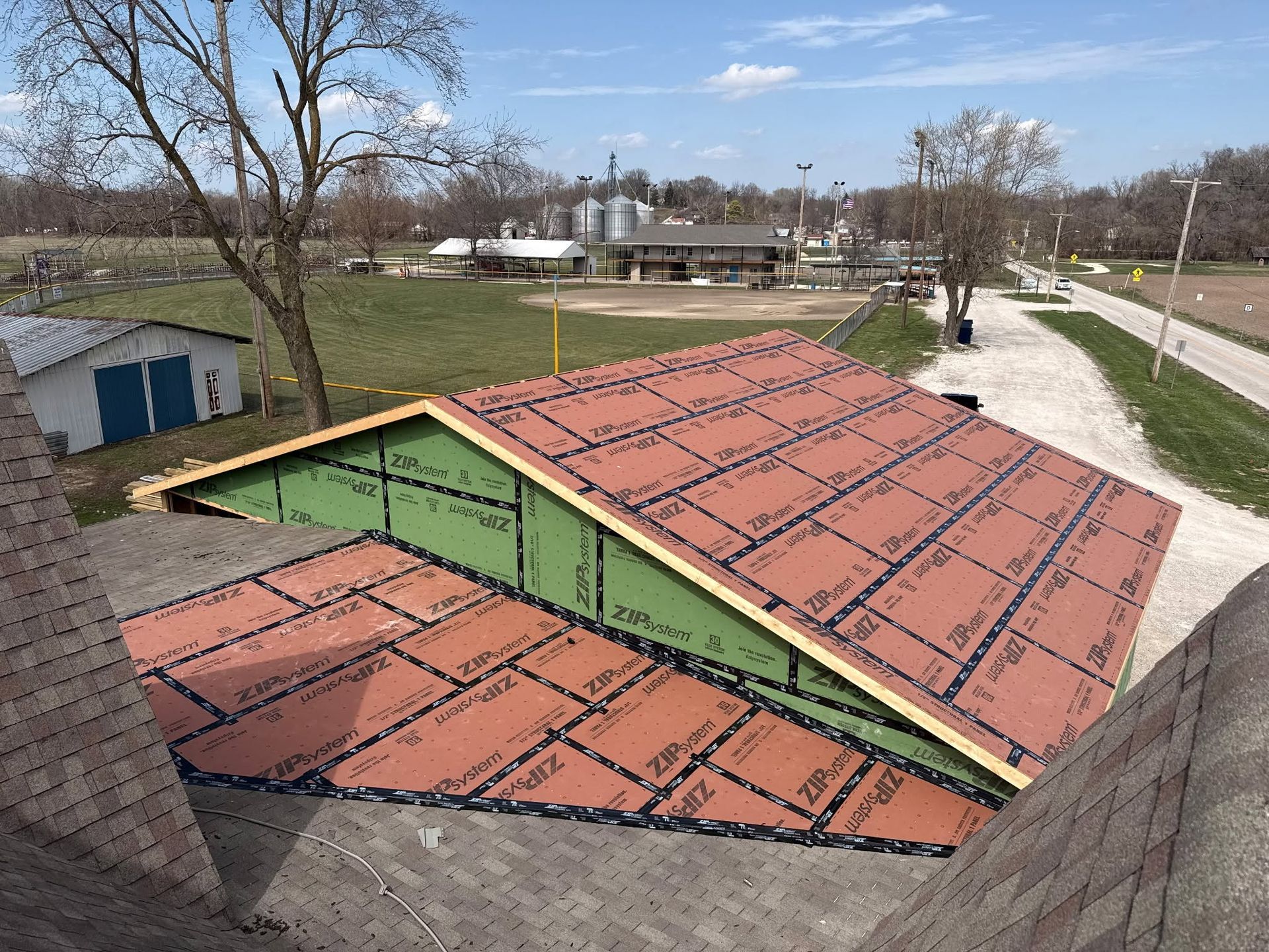 Rooftop view of red and green building roofs beside a road and open field
