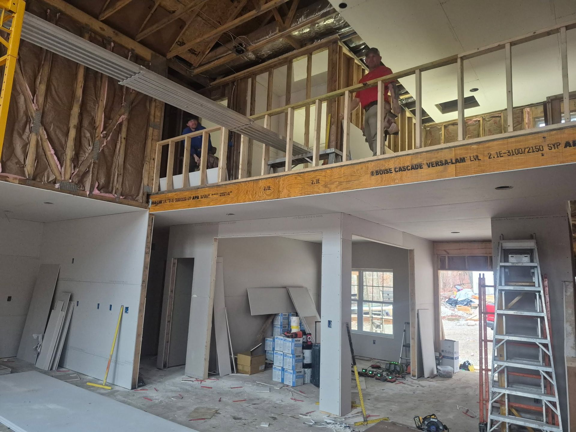 Interior of a home under renovation with exposed framing, ladders, and construction materials.