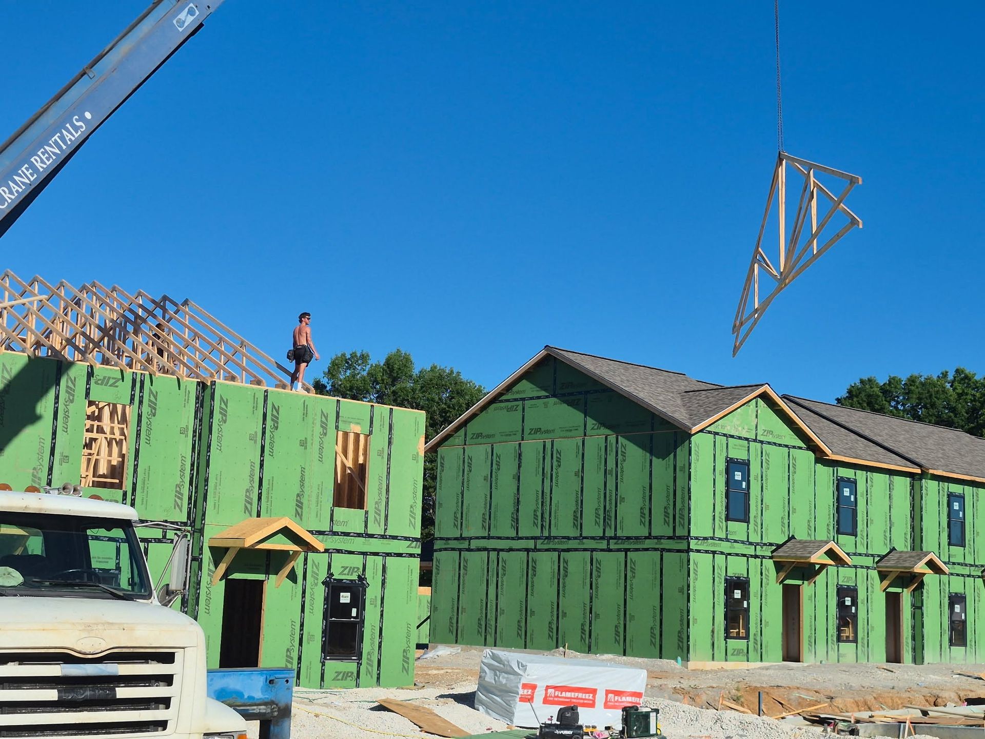 Workers installing a green house frame at a construction site with a crane overhead