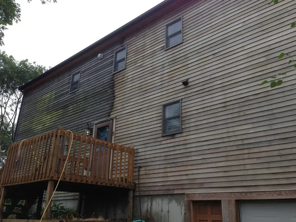 Side of house, half-cleaned siding, with deck below; comparison shows before/after pressure washing.