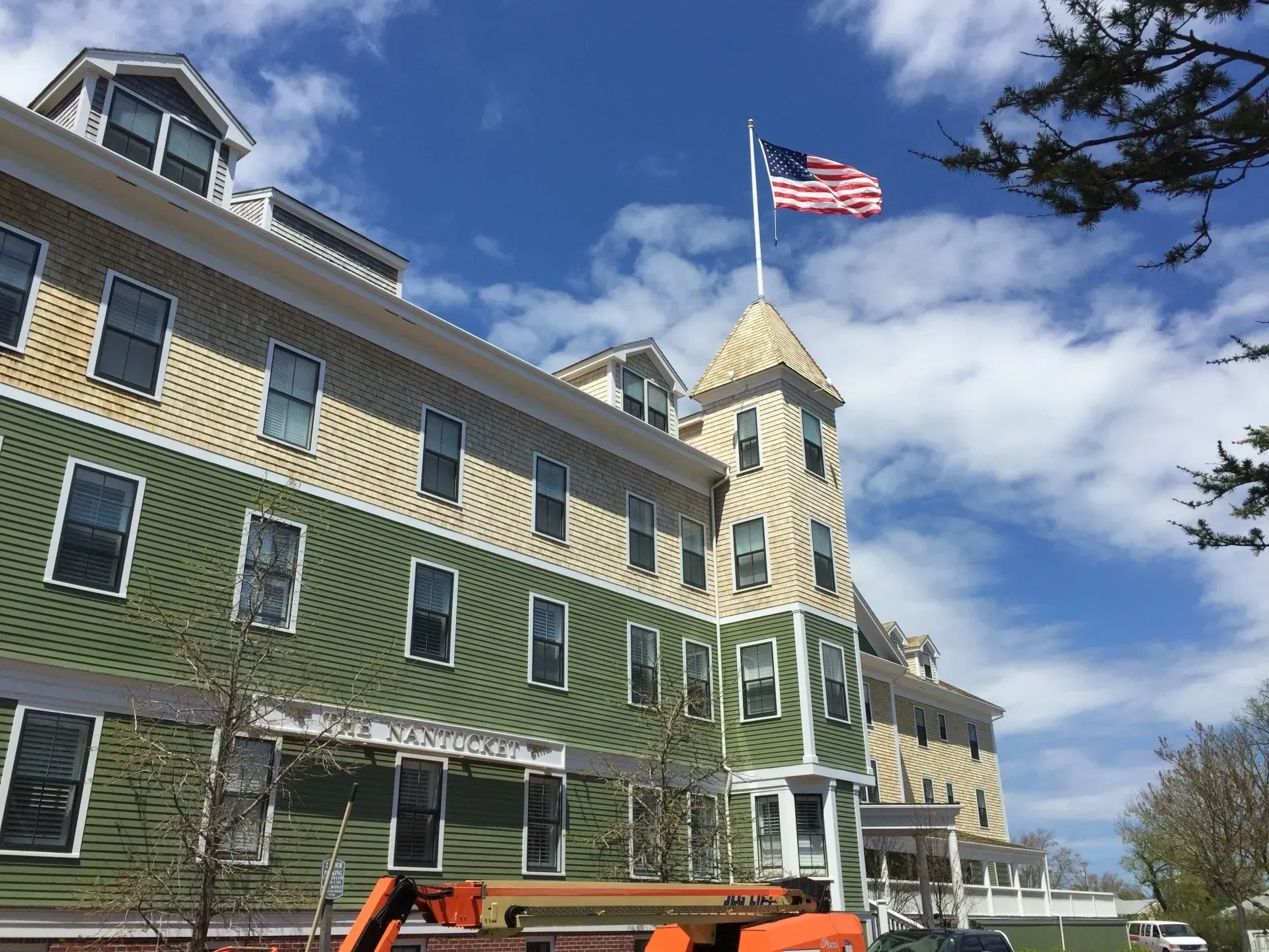 Hotel building with a green and beige exterior, American flag waving on top.