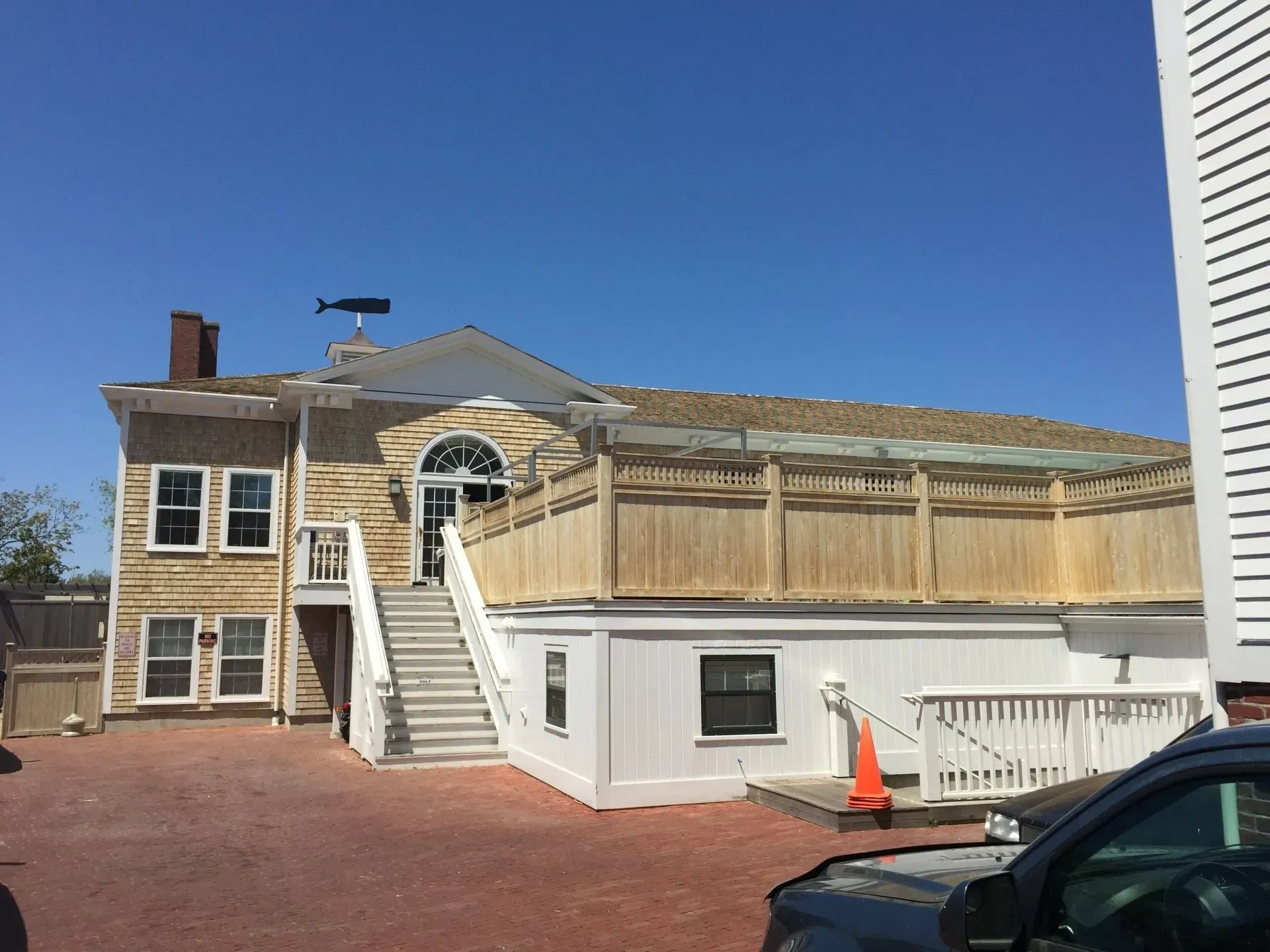 Exterior view of a two-story building with white, tan, and brown siding and a staircase leading to the entrance.