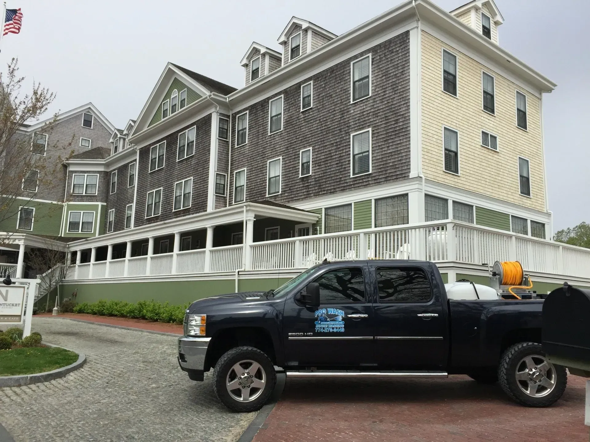 Dark blue pickup truck parked in front of a multi-story building with green and gray siding.