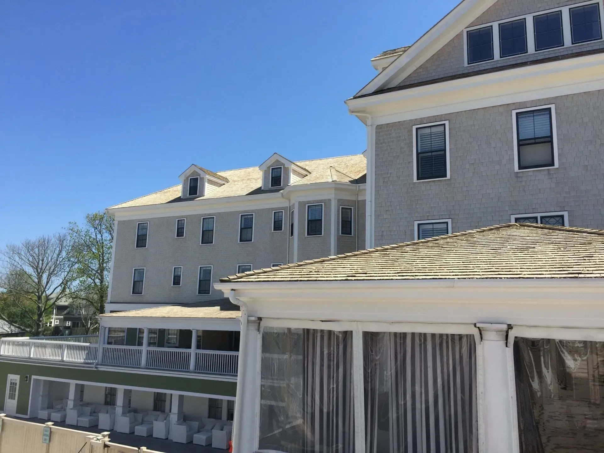Buildings with gray facades and white trim under a clear blue sky.