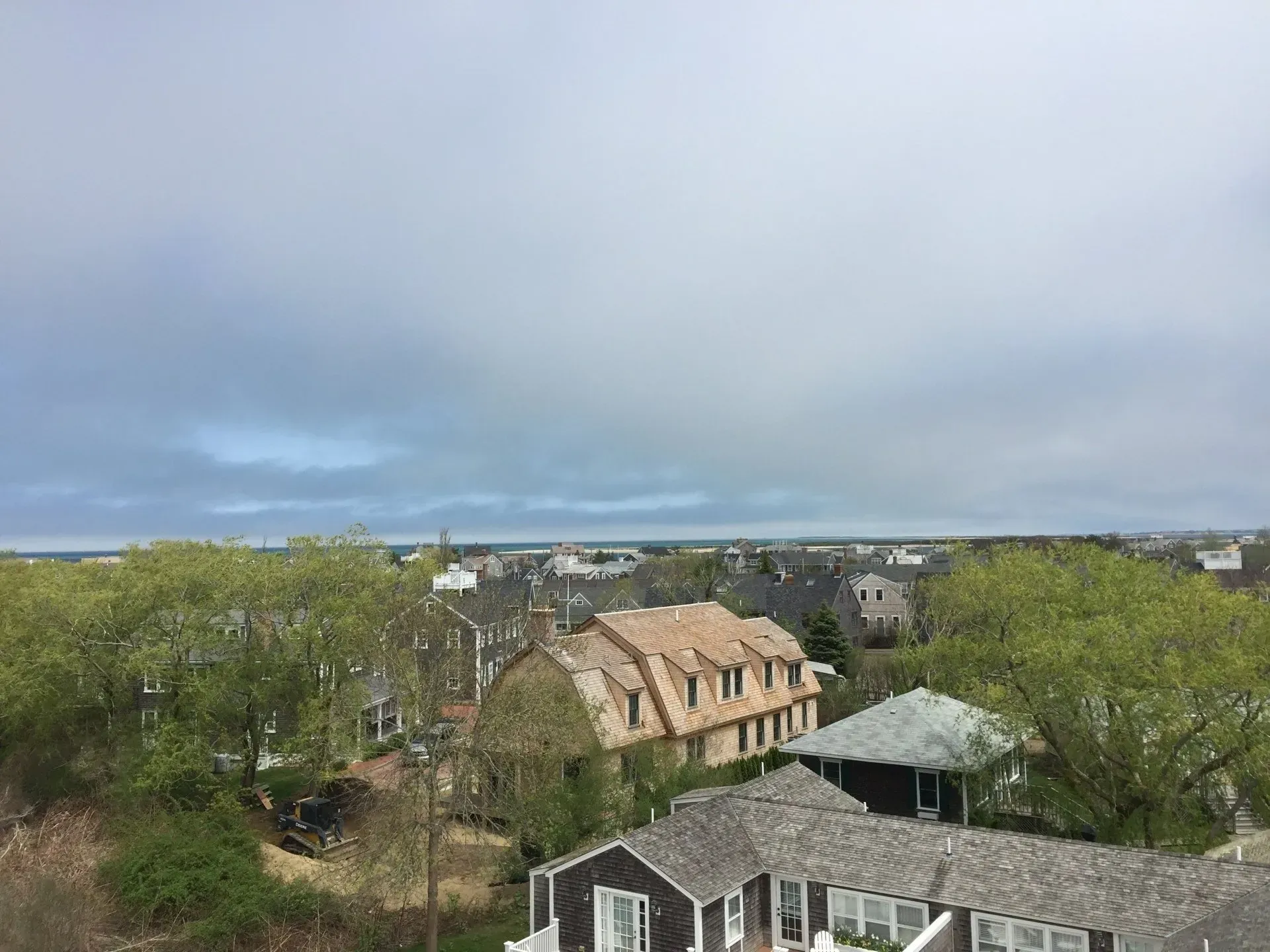 Overhead view of homes and trees under a cloudy sky.