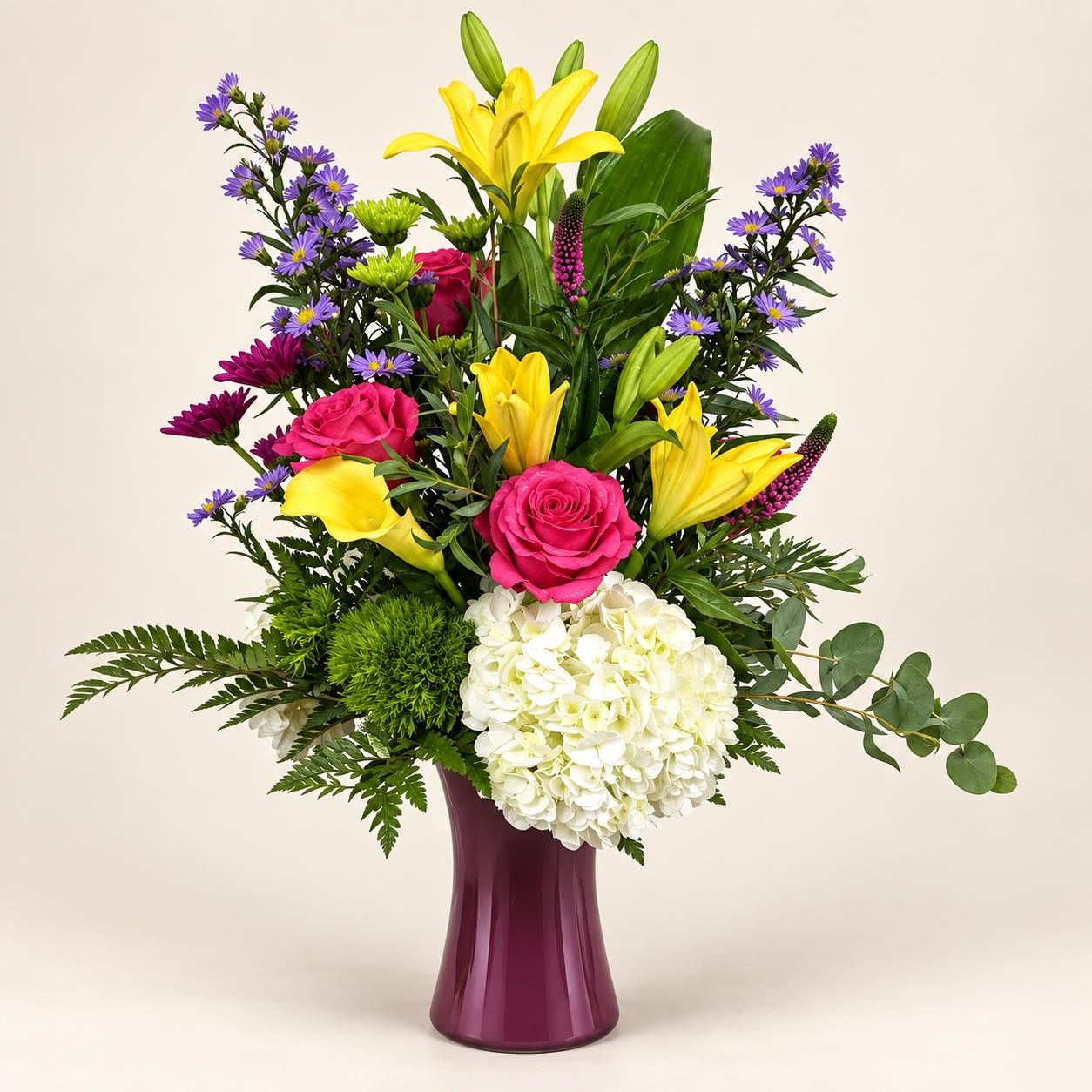 Colorful mixed flower bouquet in a purple vase on a plain background