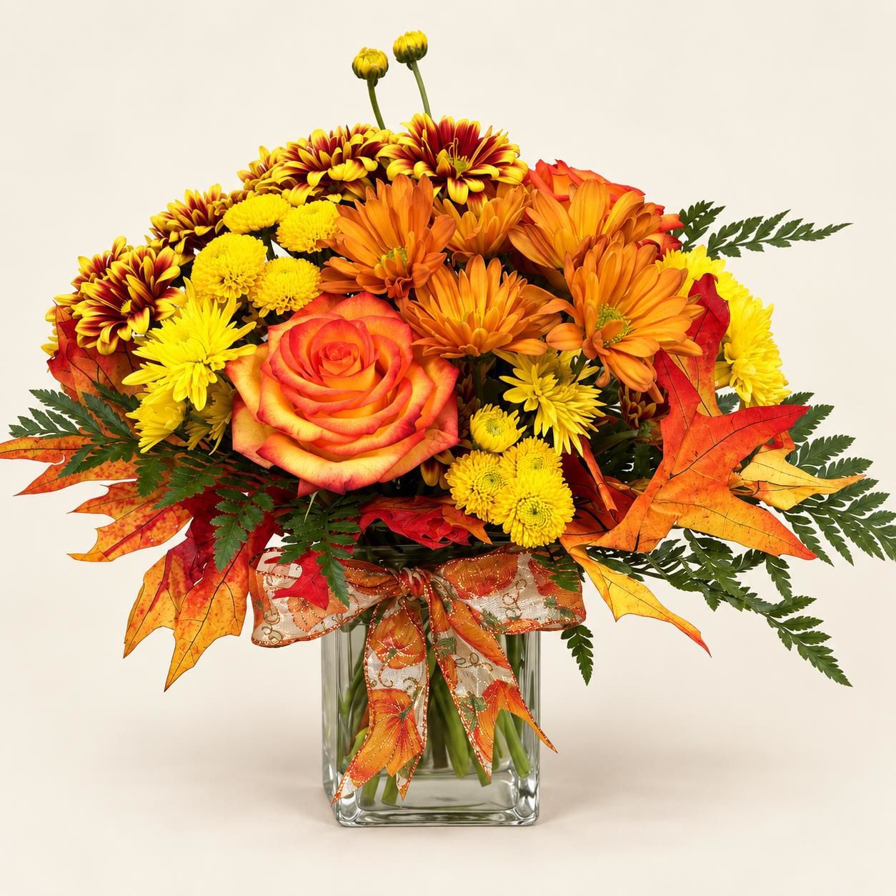 Autumn bouquet of orange, yellow, and red flowers in a glass vase