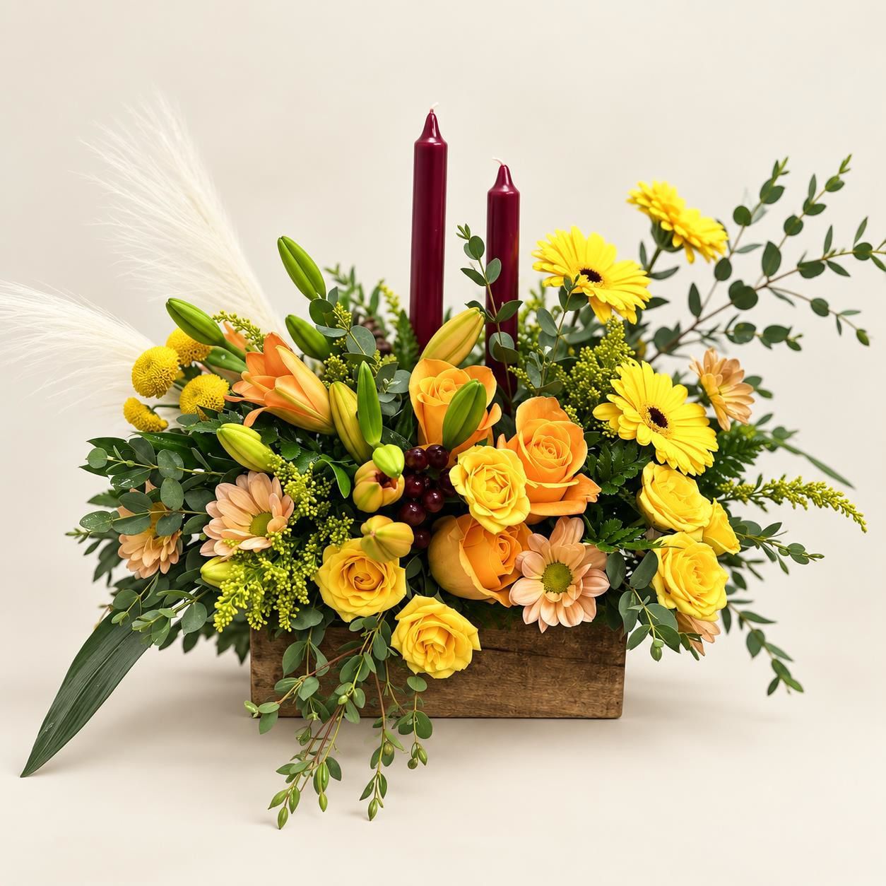 Yellow and orange floral arrangement with burgundy candles in a rectangular planter