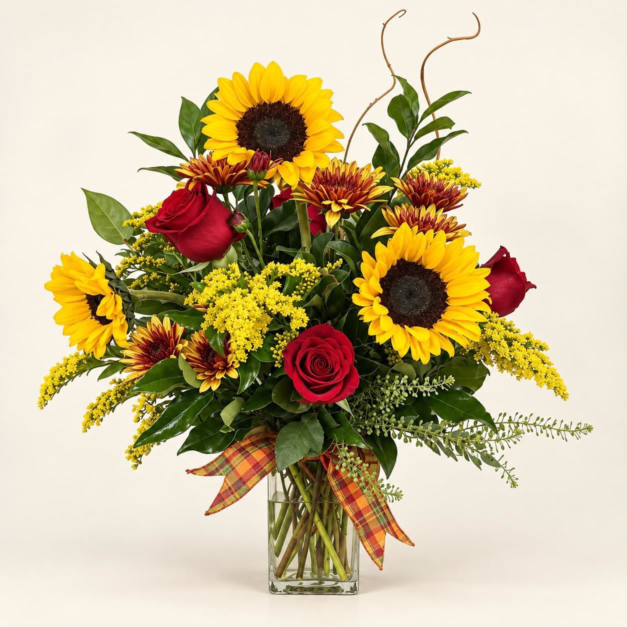 Sunflowers and red roses in a glass vase with a plaid ribbon