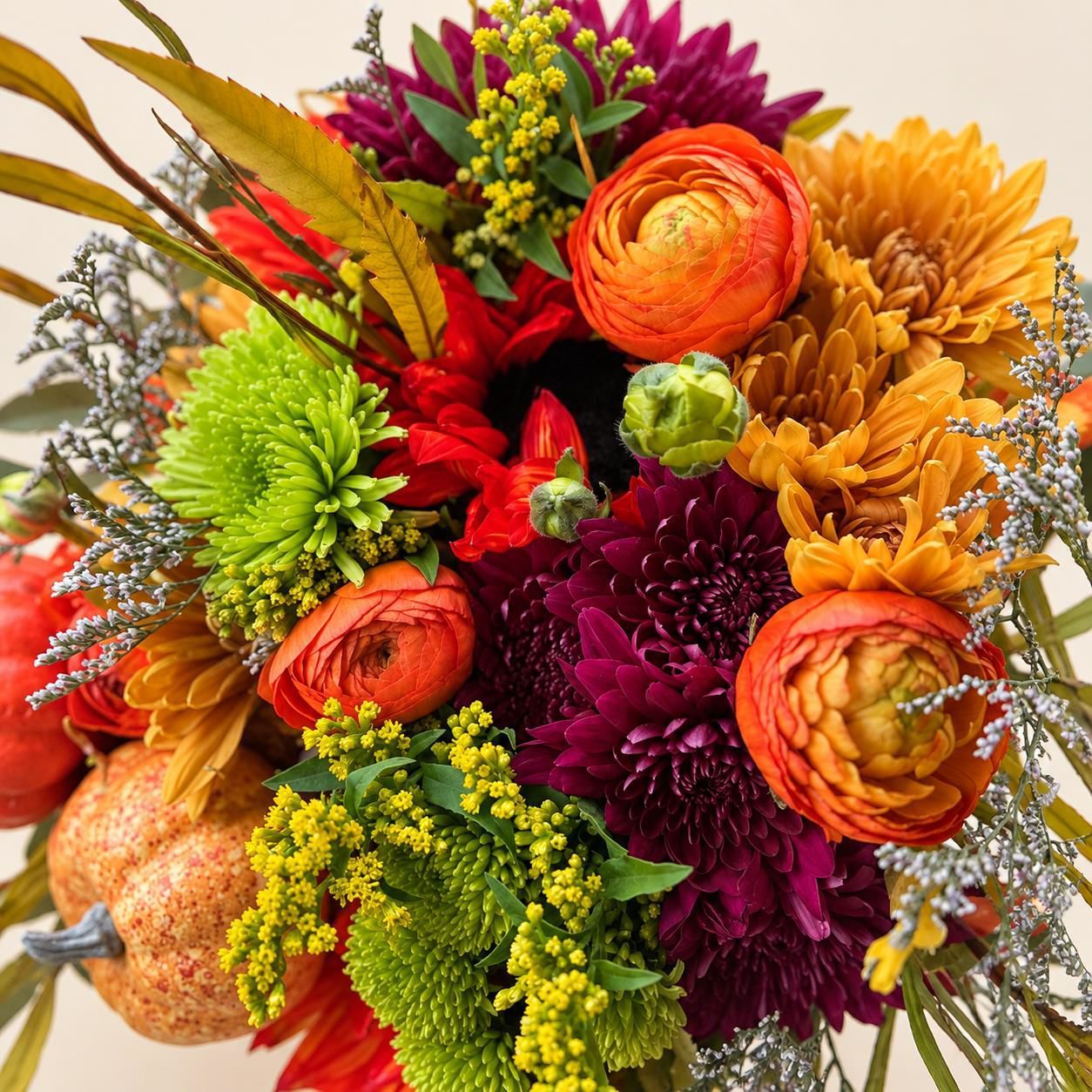 Colorful bouquet of orange, red, yellow, and green flowers with decorative gourds