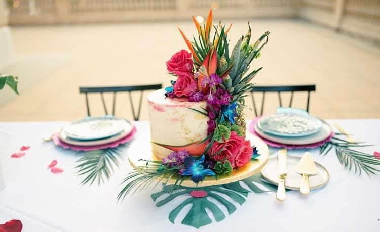 Colorful floral centerpiece on a white table set with plates and napkins for a festive meal