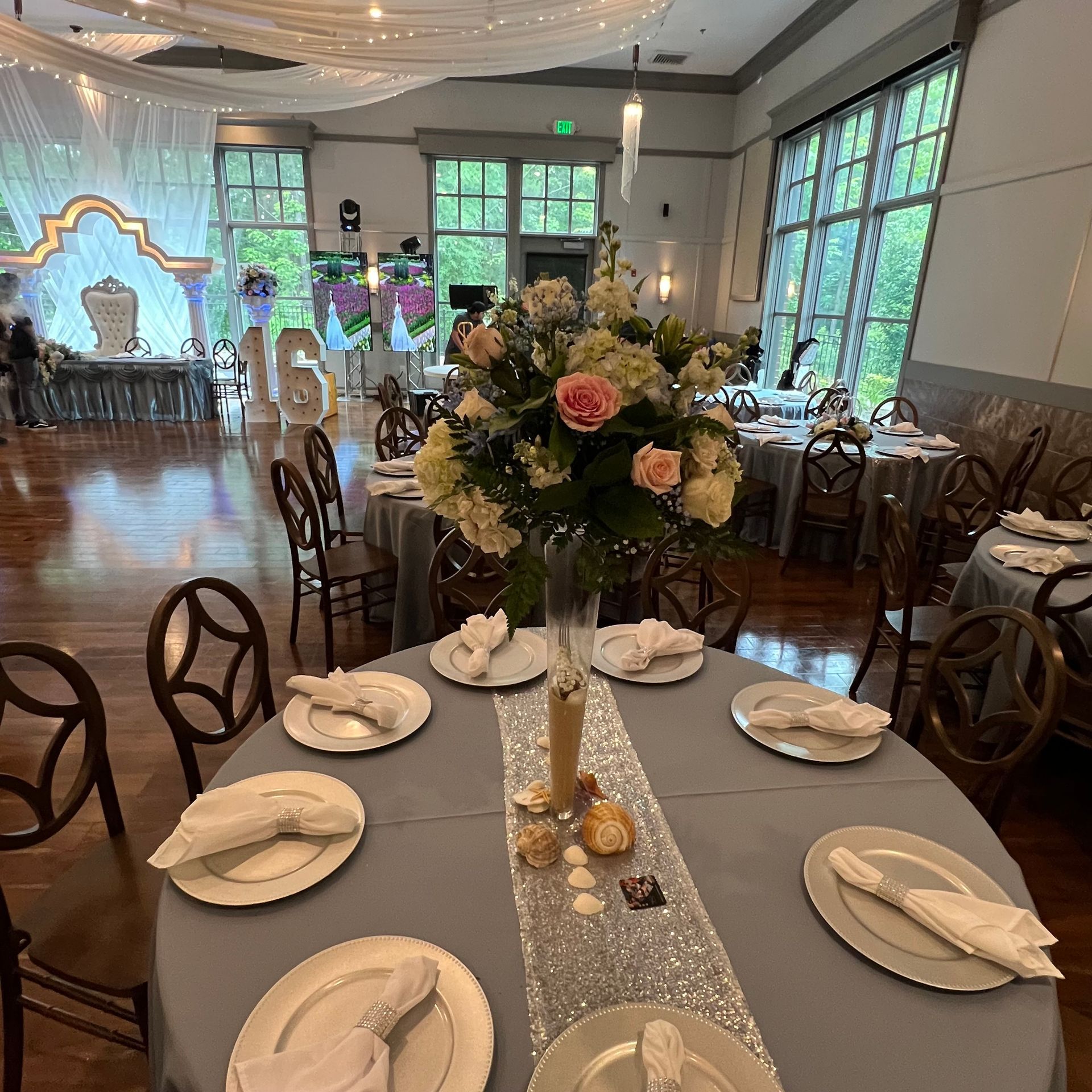 Elegant banquet hall with floral centerpieces, set dining tables, and twinkling draped ceiling lights