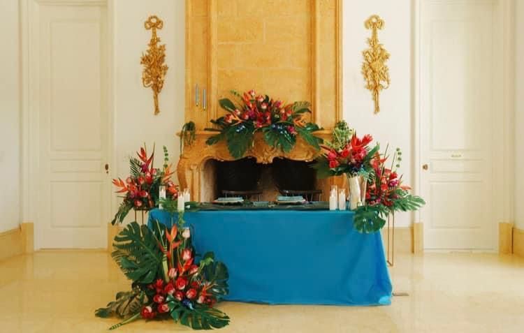 Floral arrangement on a blue-draped table in a bright, elegant room