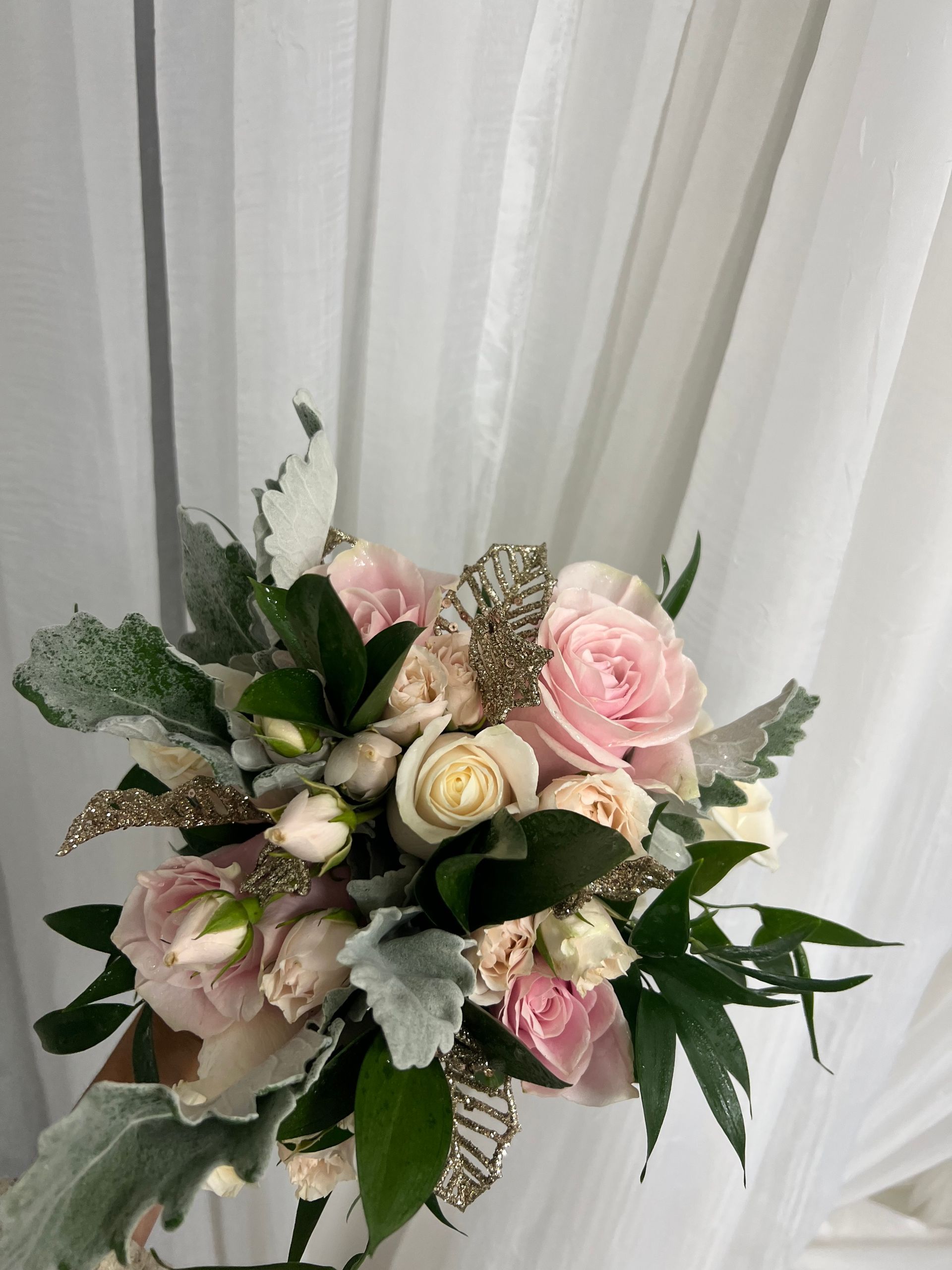 Pink and white floral bouquet with greenery, arranged against sheer white curtains