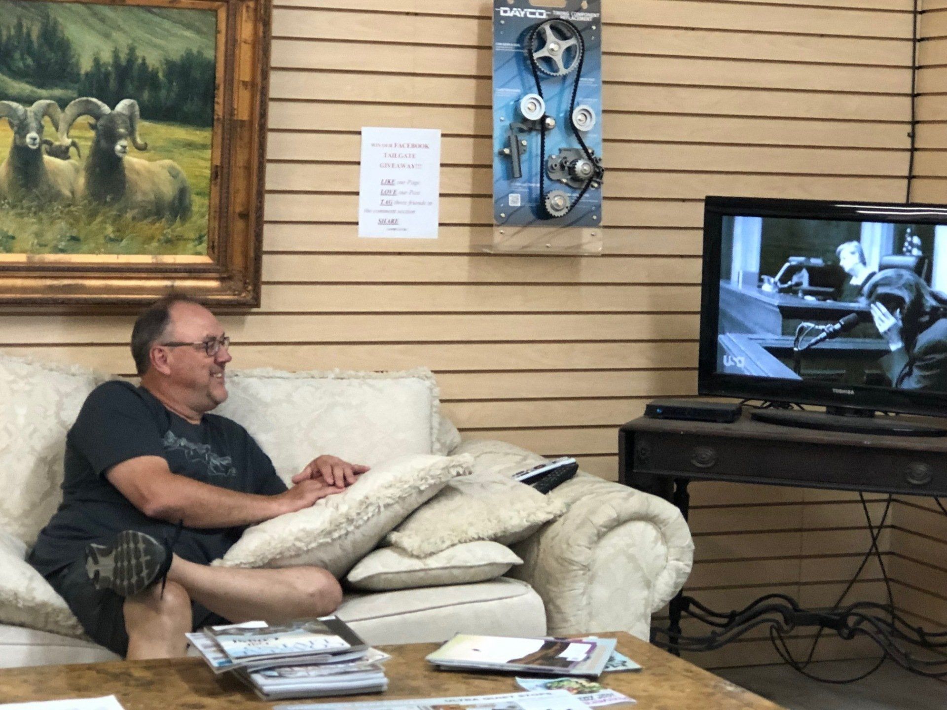 A man is sitting on a couch in front of a television.