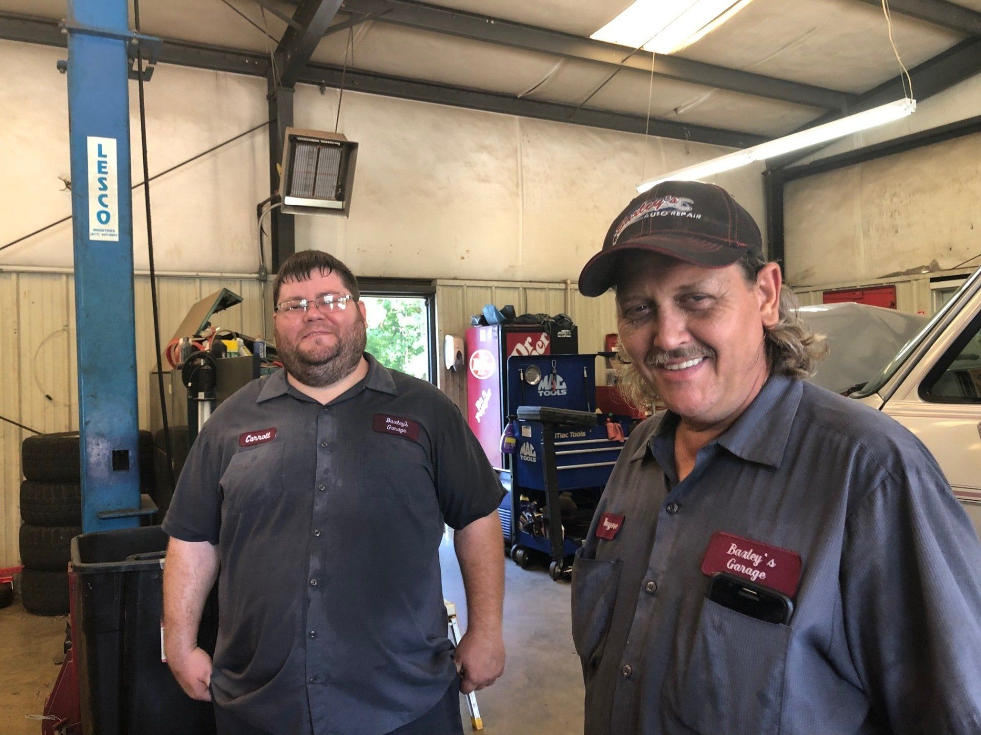 Two men are standing next to each other in a garage.