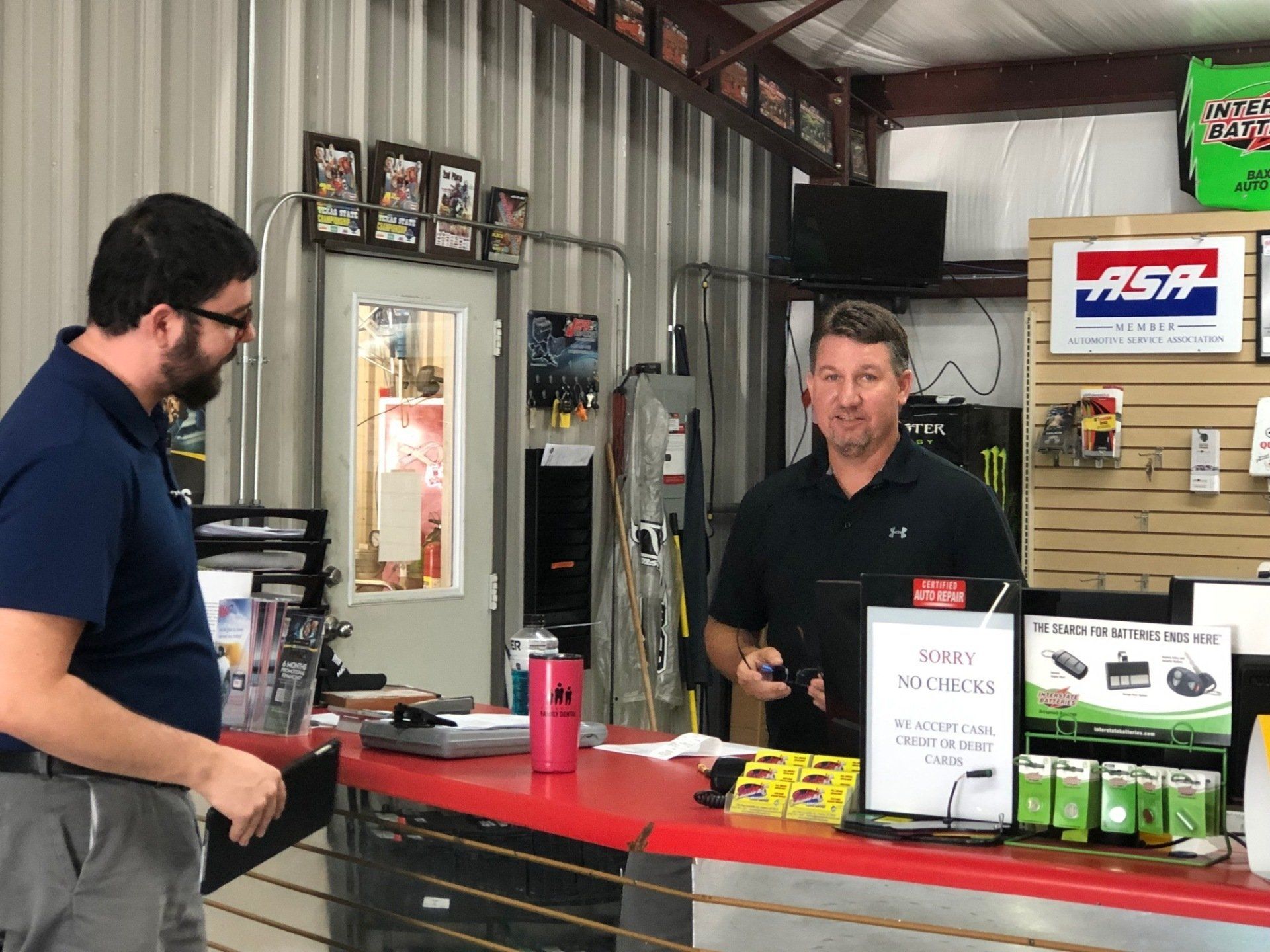 Two men are standing at a counter in a store with a sign that says ash