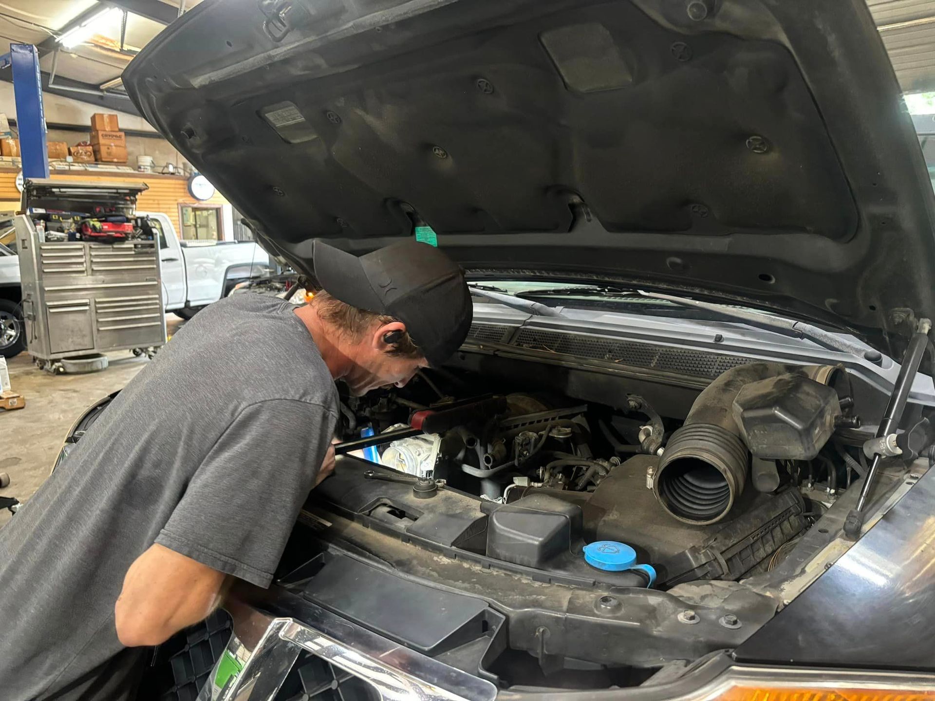 A man is looking under the hood of a car.