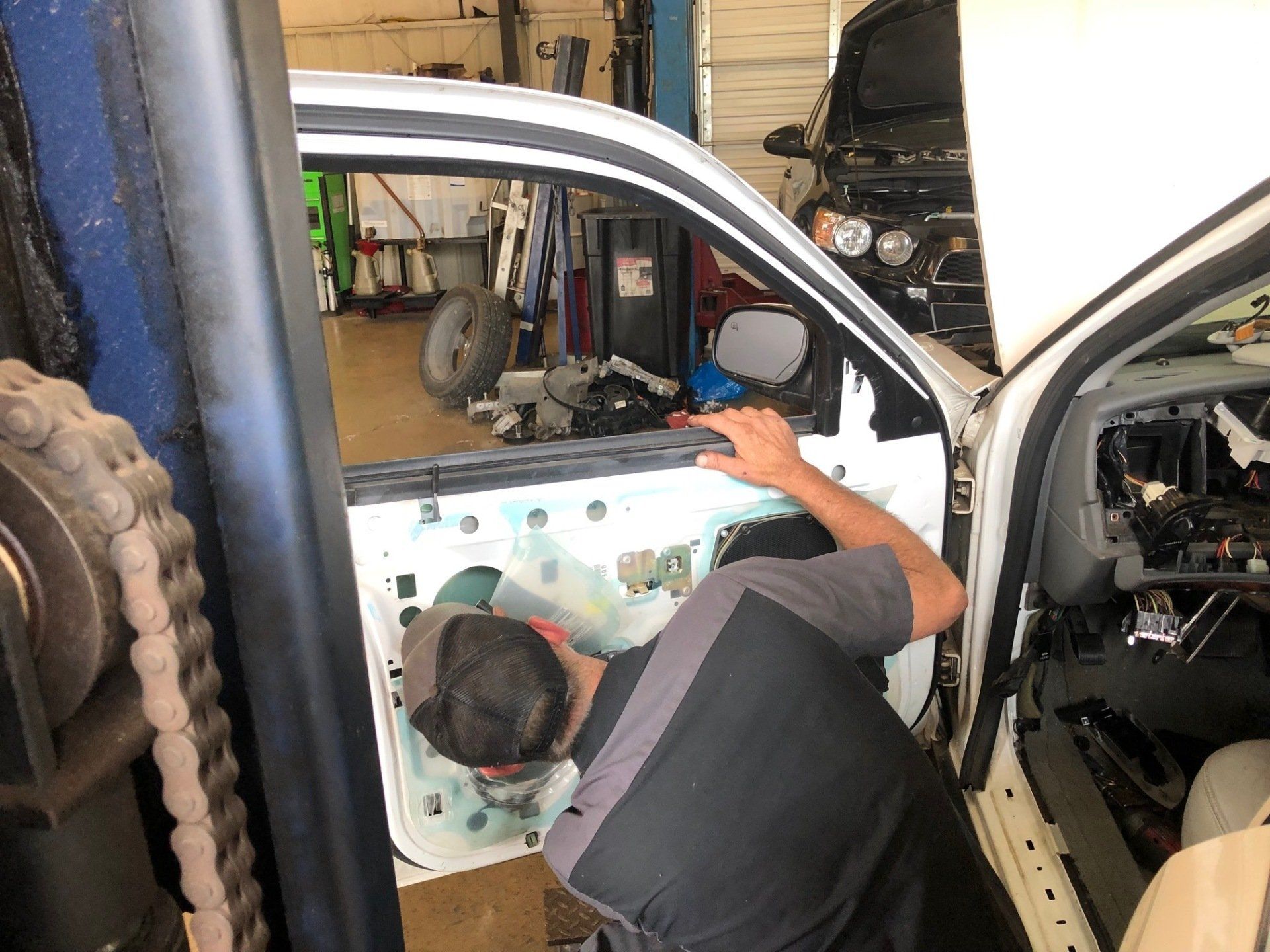 A man is working on a car door in a garage.