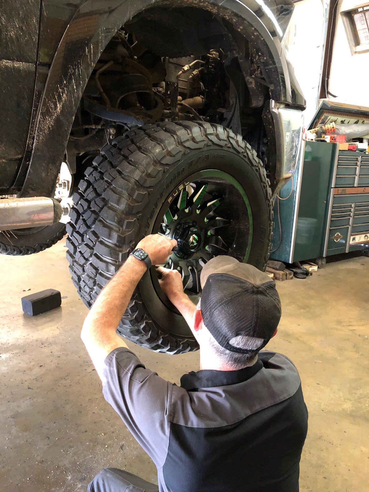 A man is working on a tire on a truck in a garage.