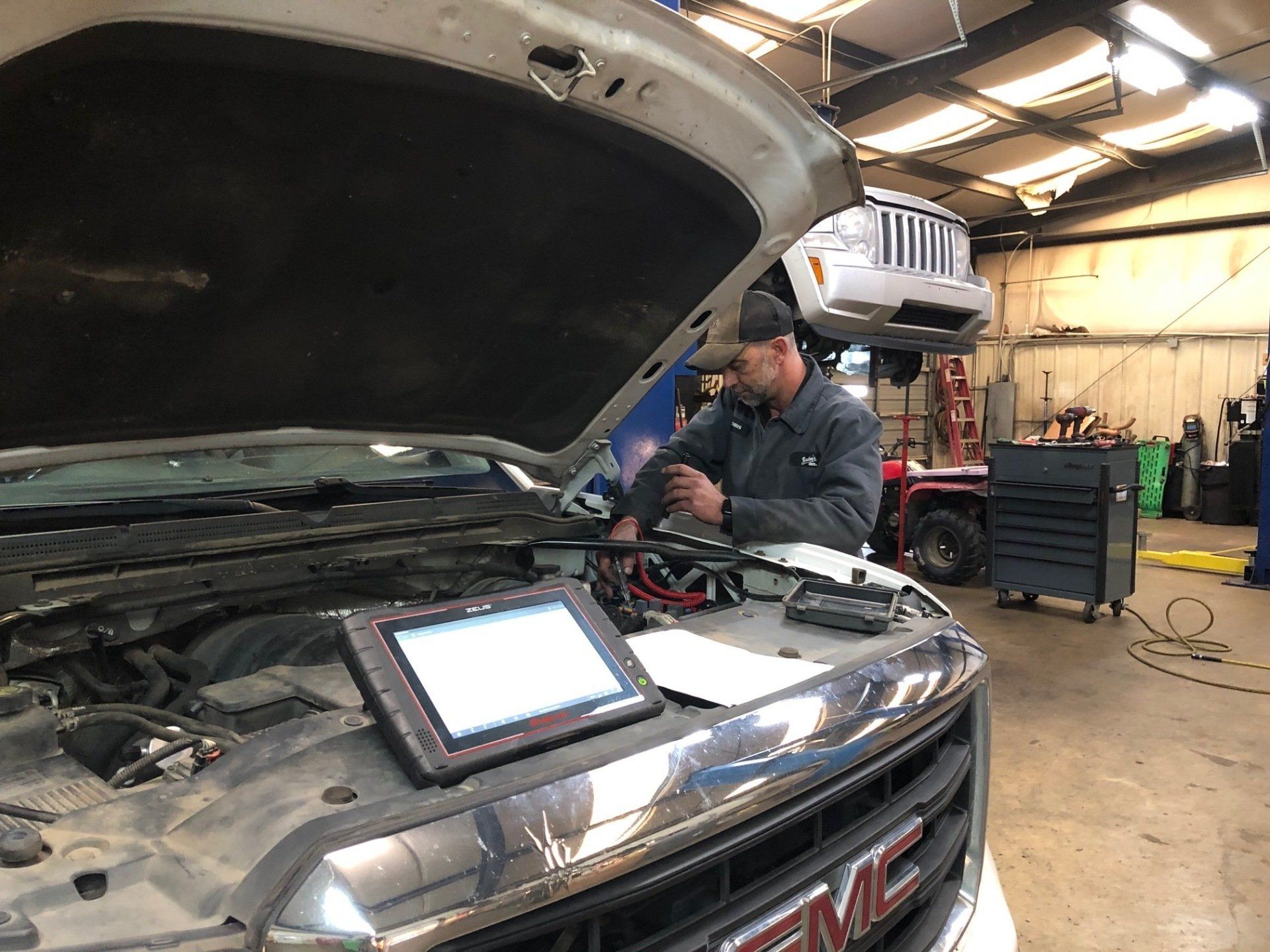 A man is working on a gmc truck in a garage.