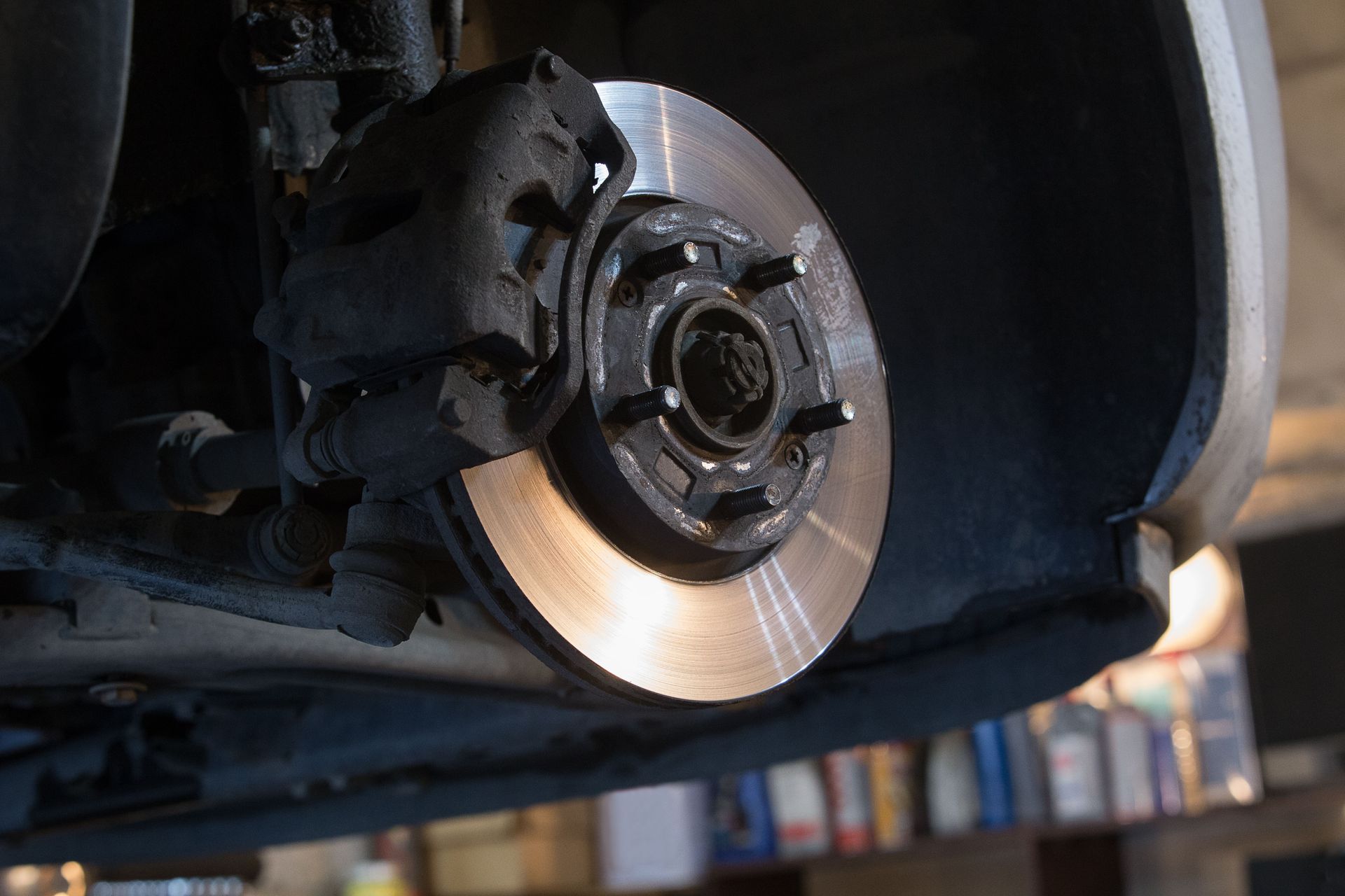 A close up of a brake disc on a car in a garage.