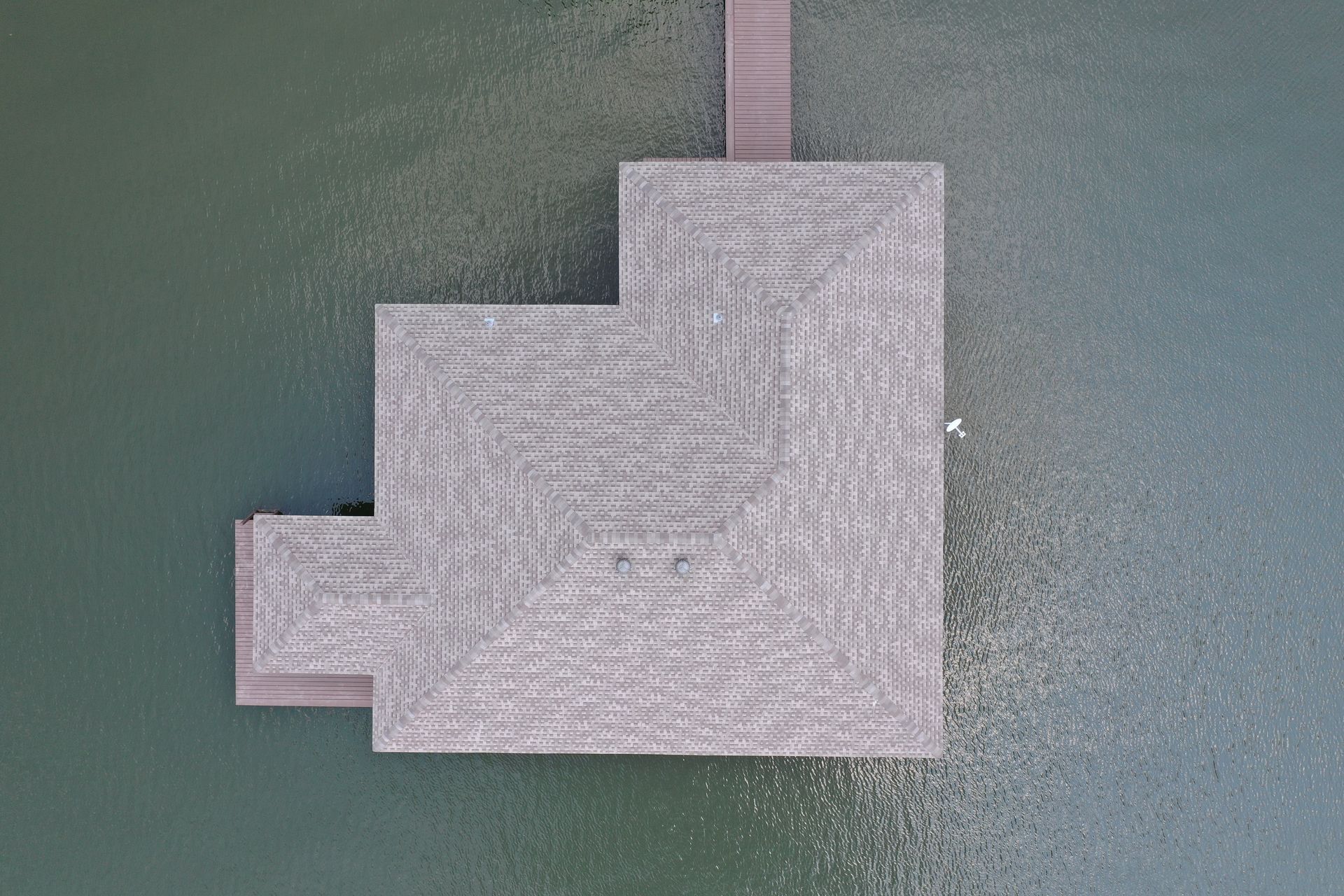 Gray geometric carpet sample with stepped layers and a pink tab on a green background