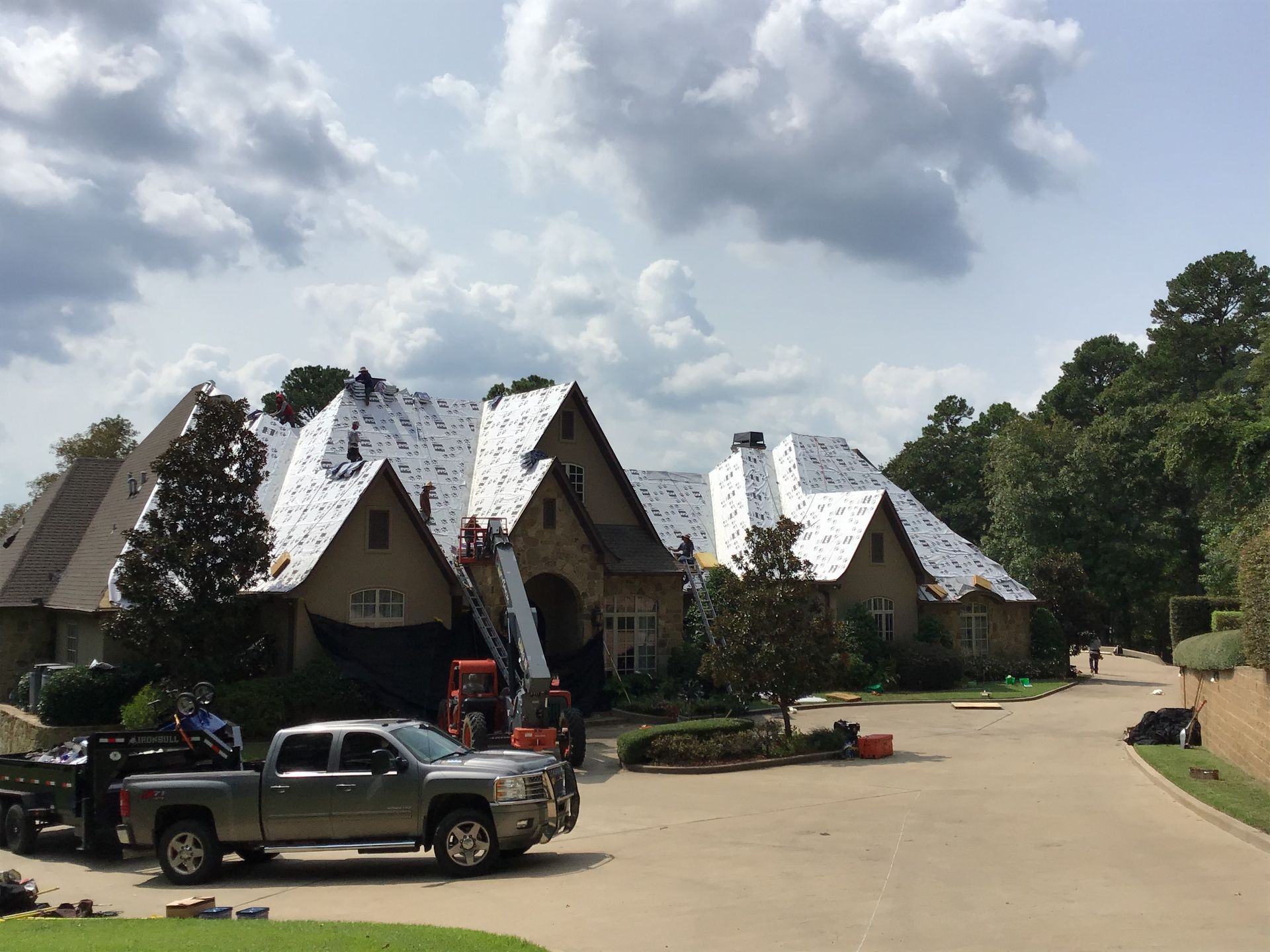Construction site with A-frame houses, pickup trucks, and workers under a cloudy sky
