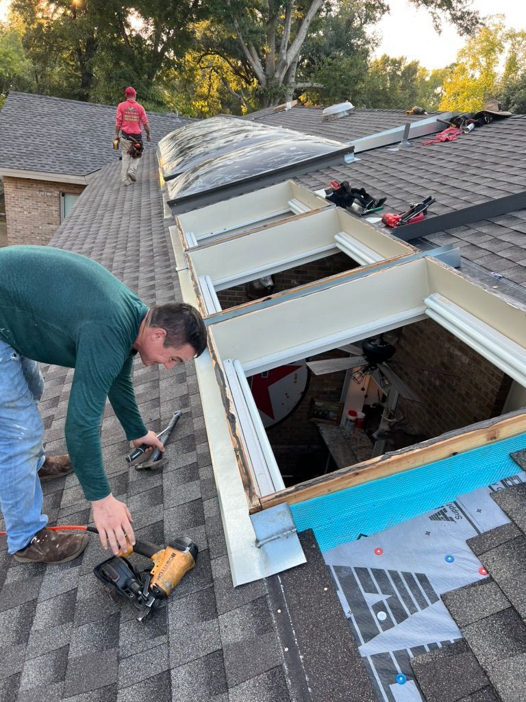 Workers repairing a roof skylight, with tools and open roof panels on a house.