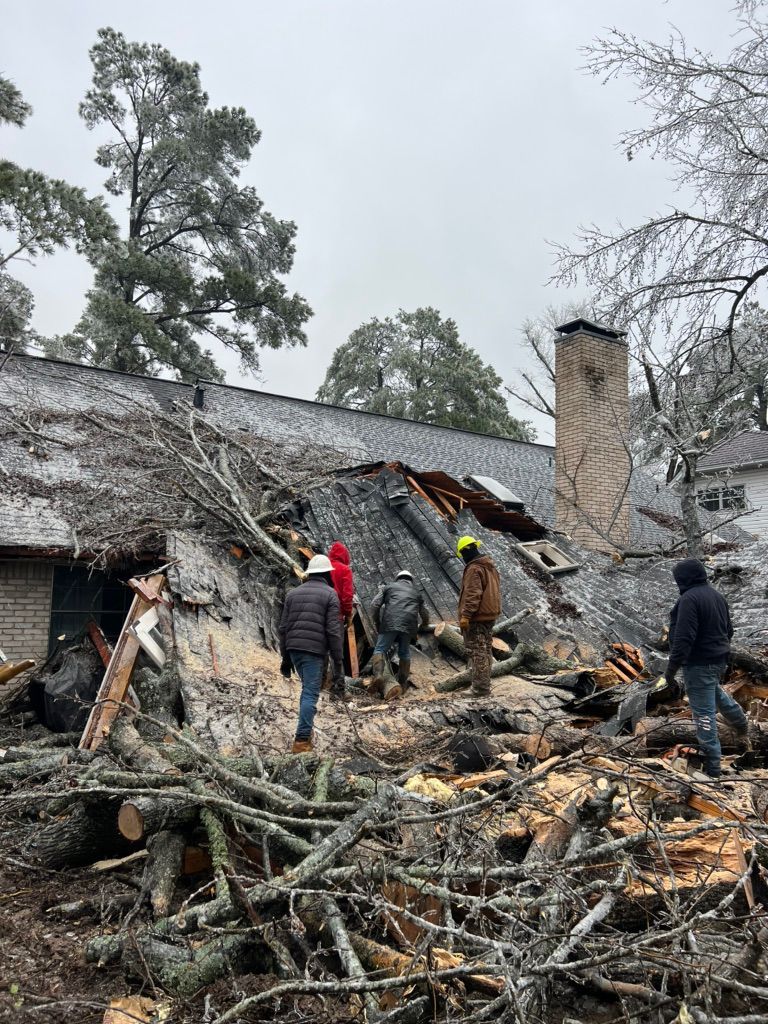 People inspecting storm damage on a collapsed roof amid fallen branches and debris