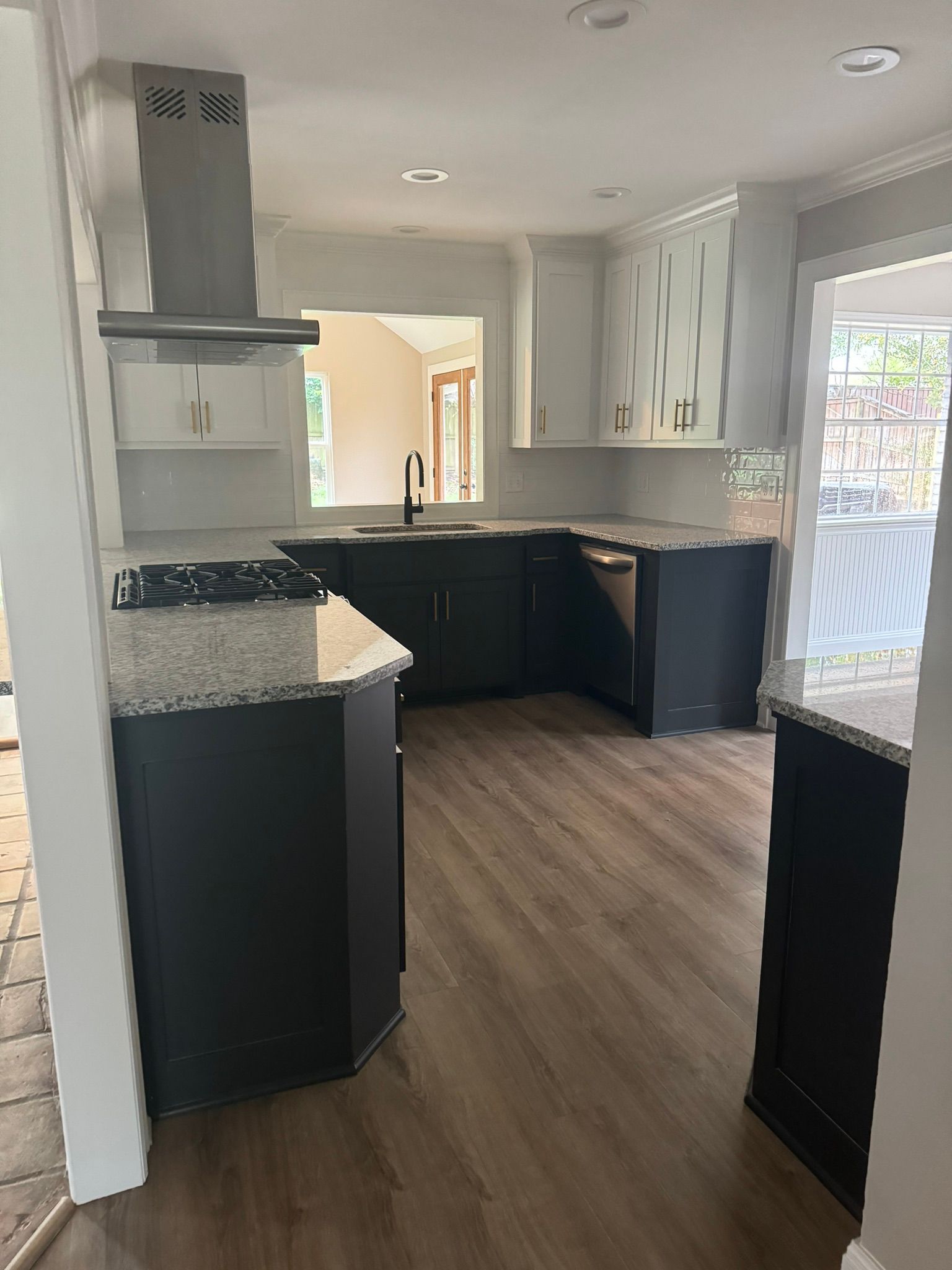 Modern kitchen with dark cabinets, white countertops, wood floor, and bright natural light